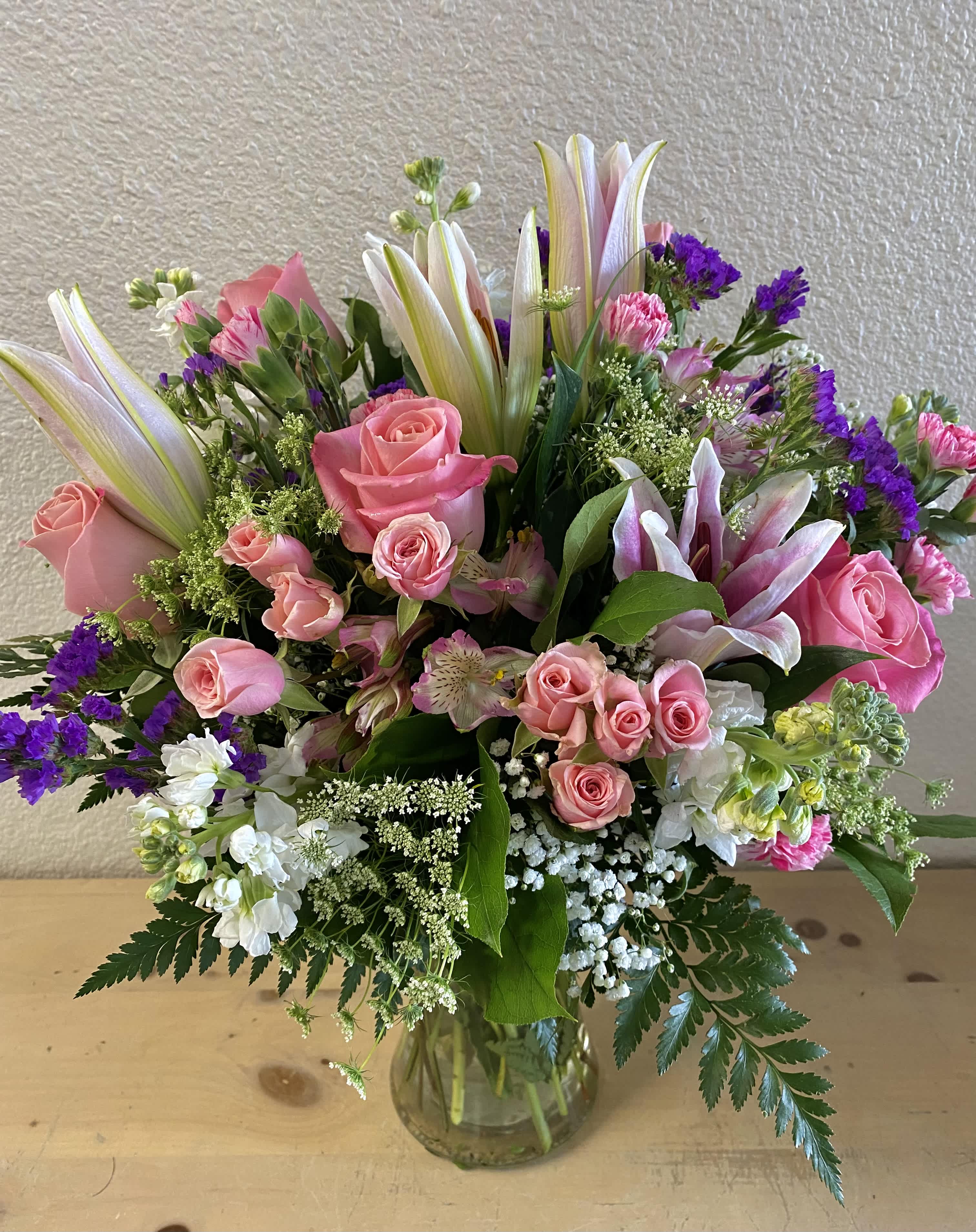 Pink roses and lilies arranged in a clear glass vase
