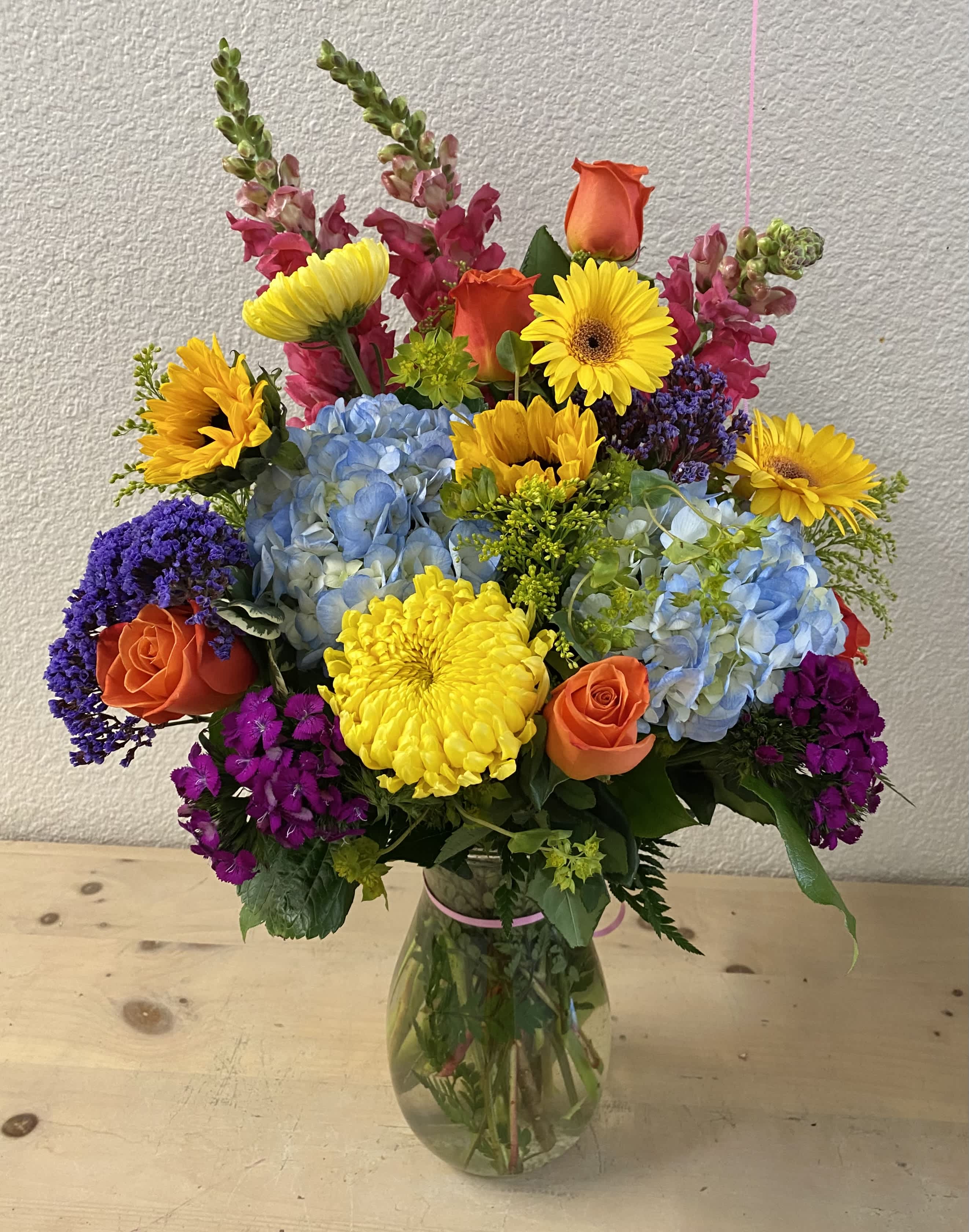 Colorful mixed bouquet in a glass vase with roses, hydrangeas, and daisies