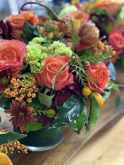 Coral roses and green hydrangeas in a dark vase