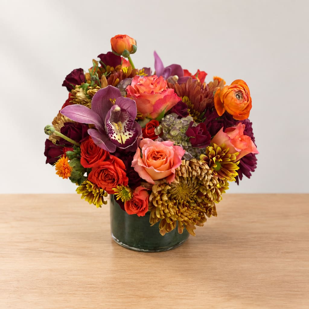 Mixed bouquet of roses, orchids, and chrysanthemums in a glass vase