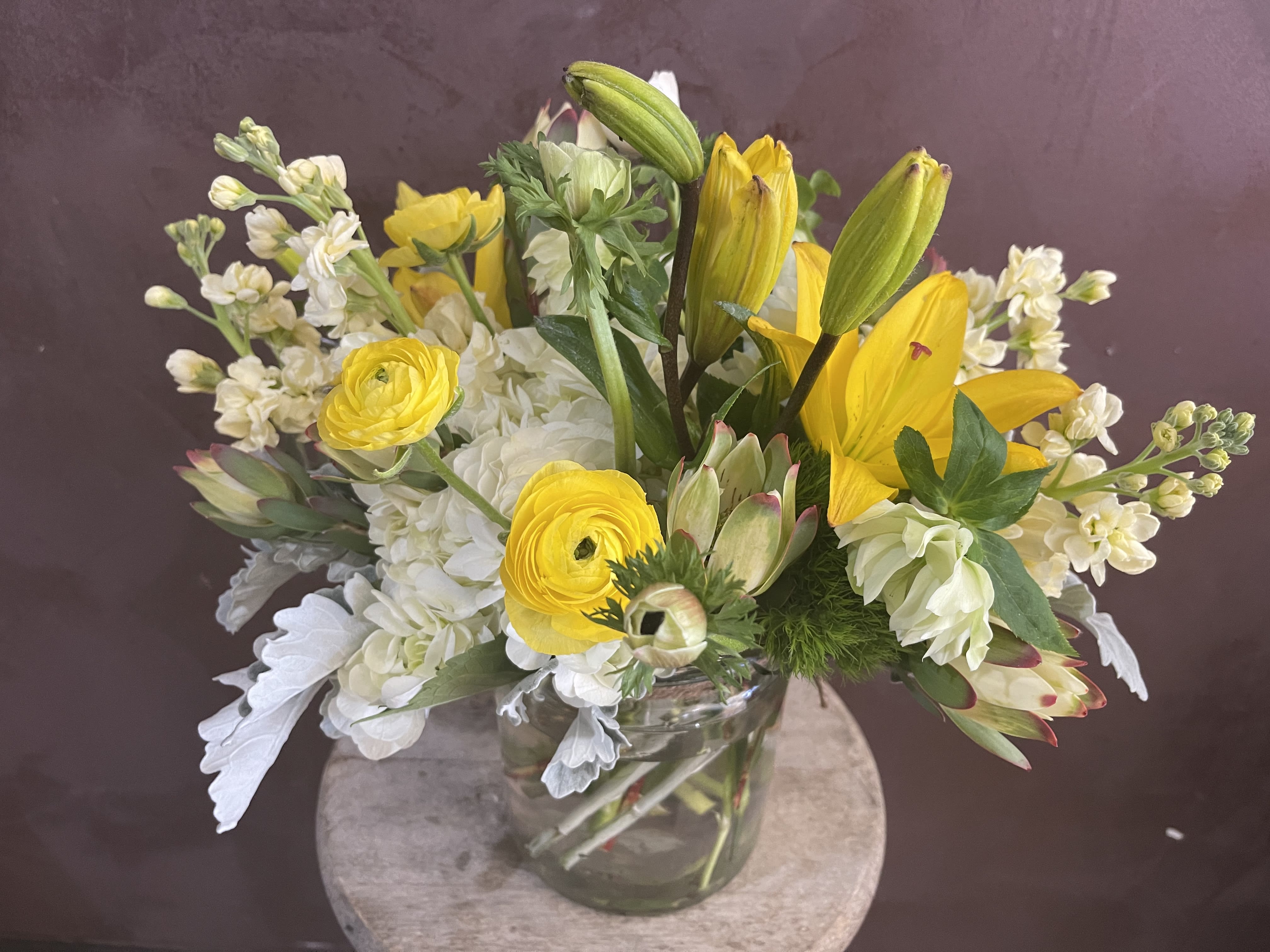Yellow lilies and white flowers in a clear glass vase