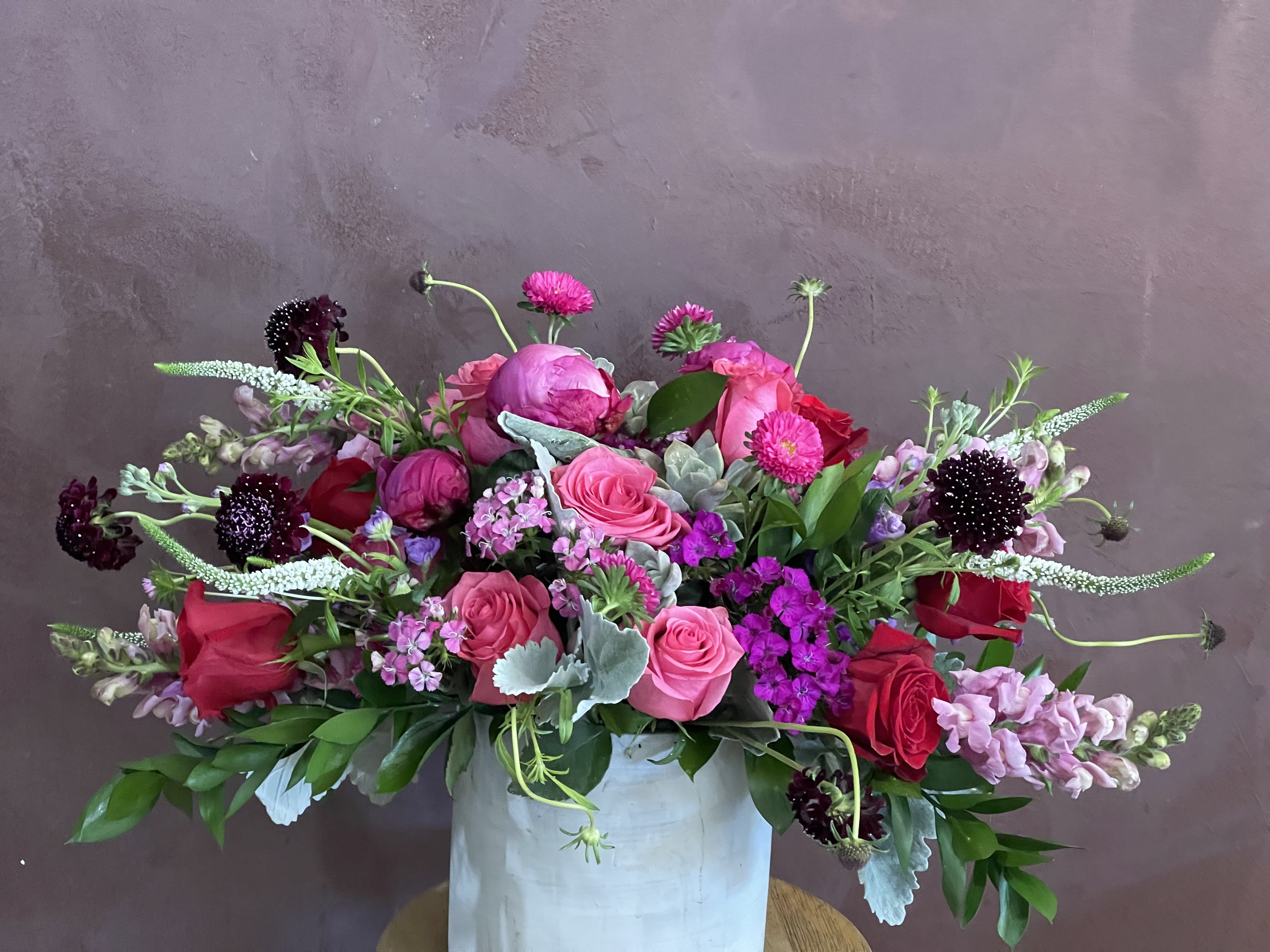 Pink and red mixed flower arrangement in a white vase