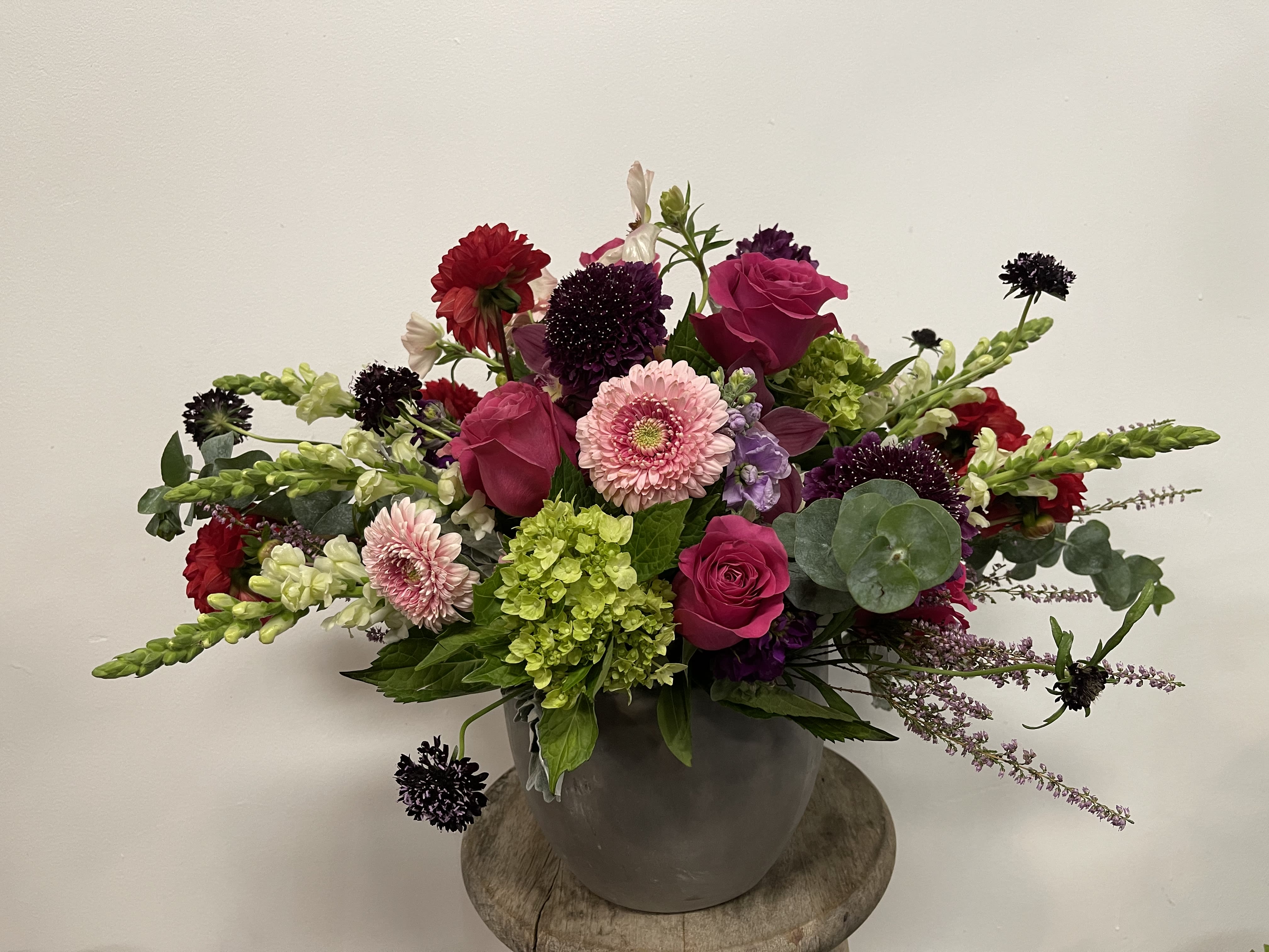 Mixed bouquet of pink roses, gerbera daisies, and green hydrangea in a gray vase