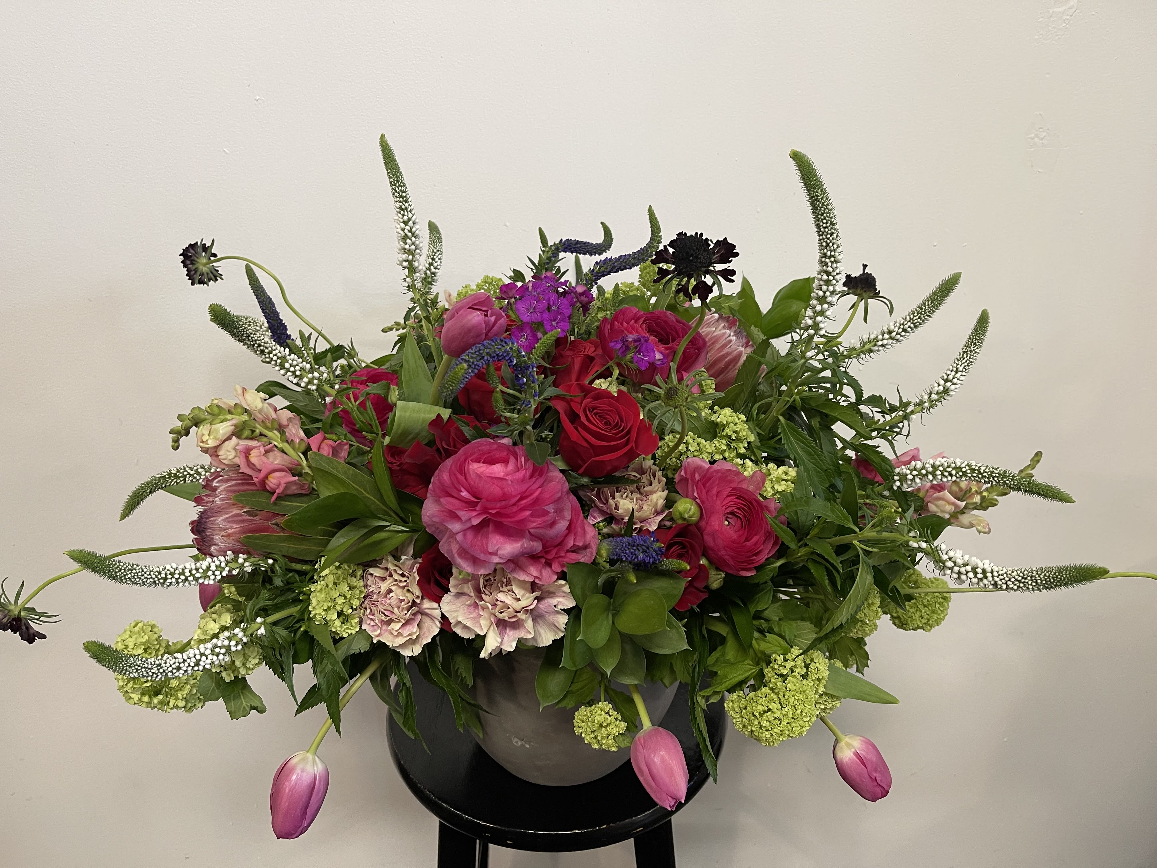 Mixed pink and red floral arrangement in a dark vase