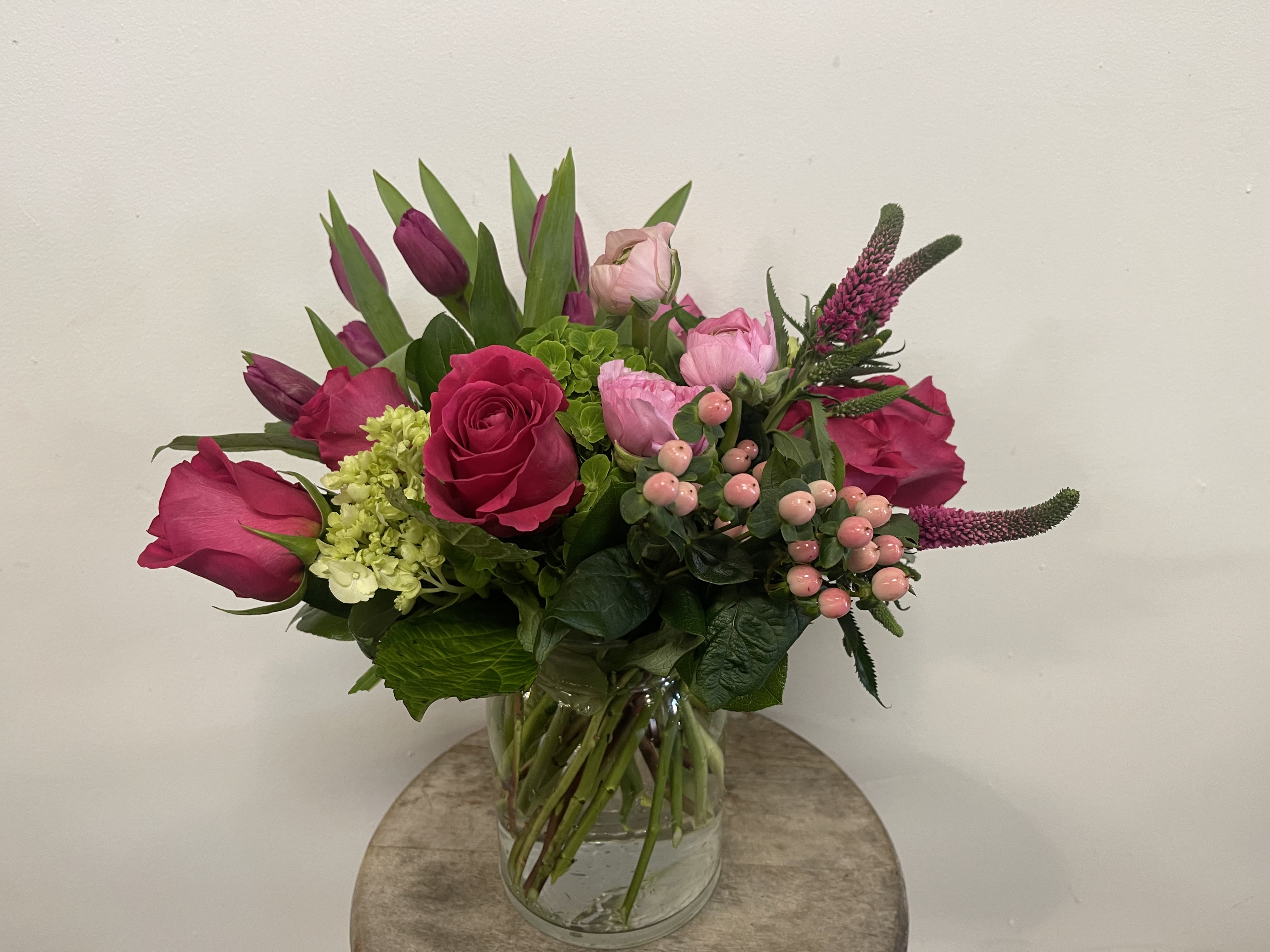Pink roses and tulips arranged in a glass vase