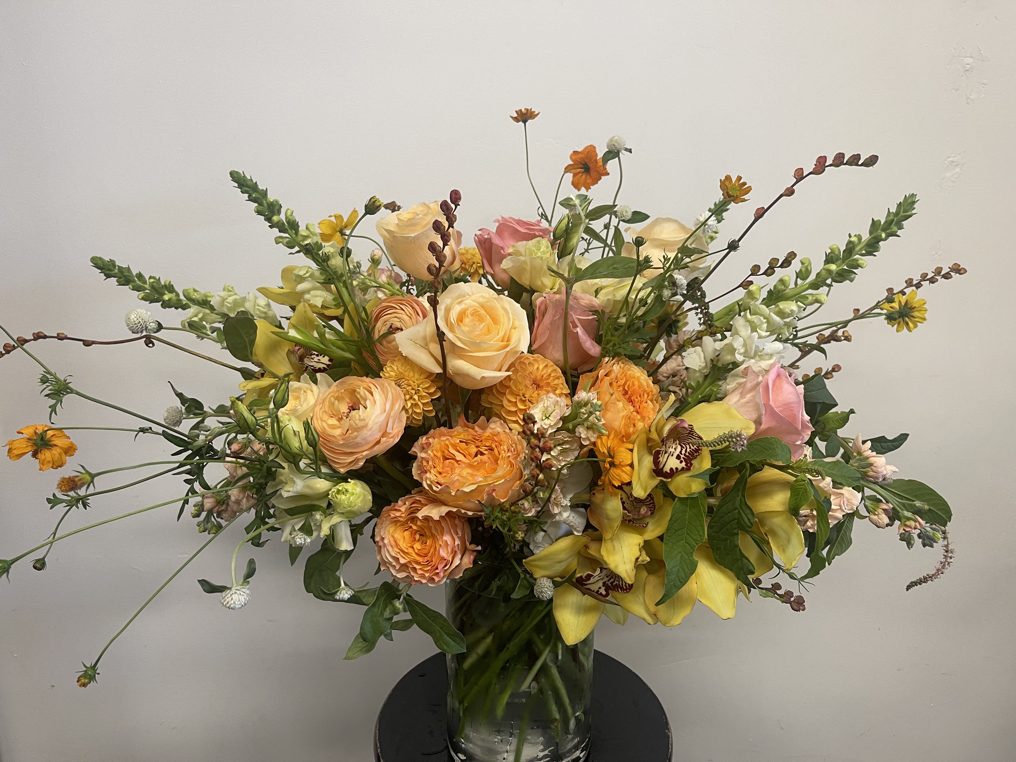 Large mixed bouquet of roses, orchids, and yellow blooms in a glass vase