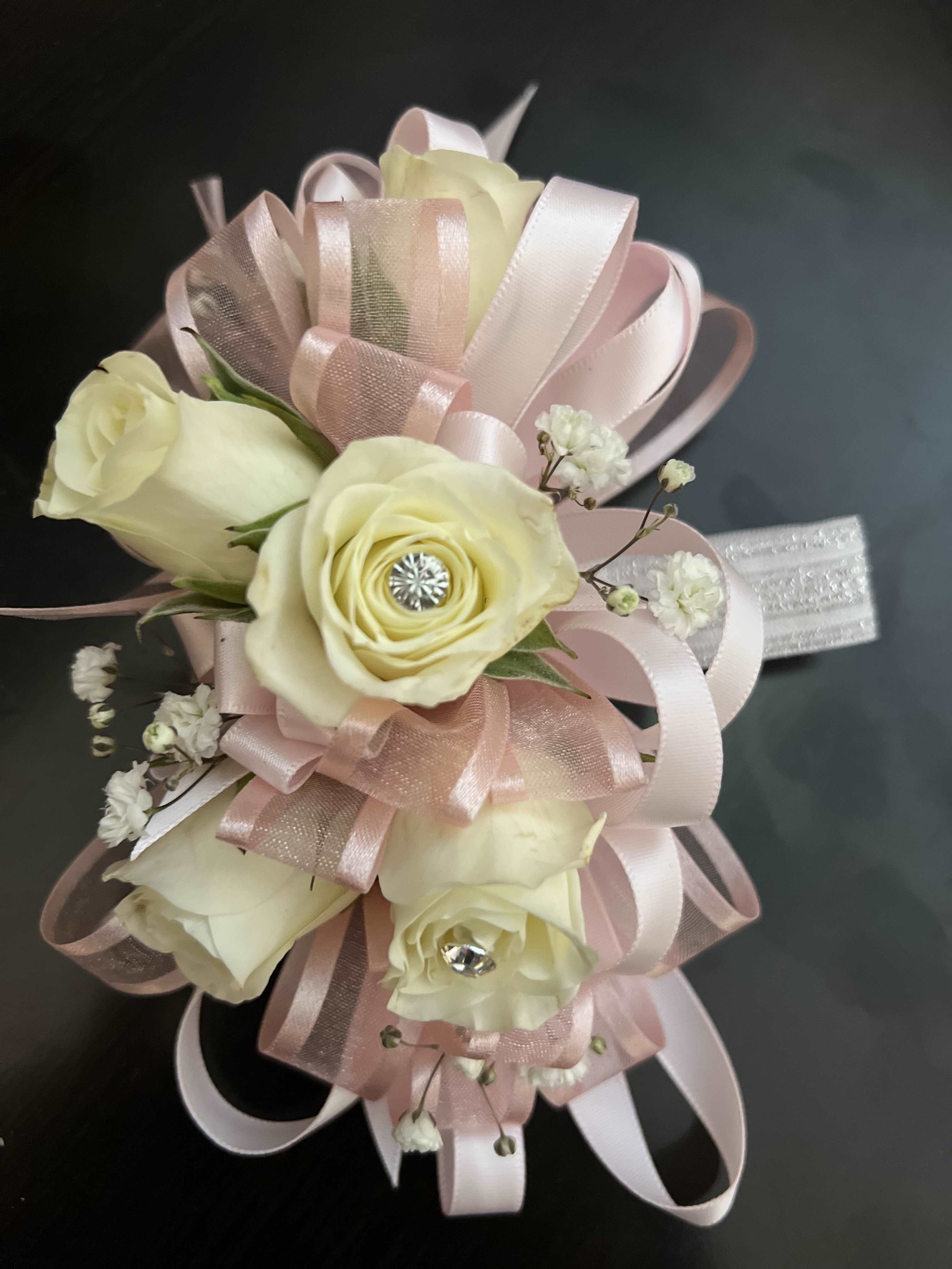 Cream roses with pink ribbon loops and small white filler flowers