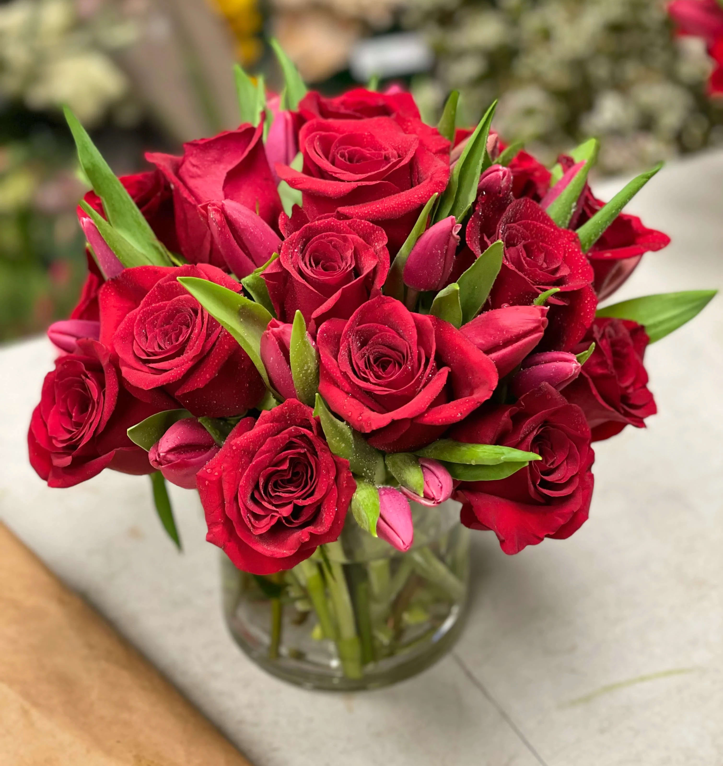 Red roses and pink tulips arranged in a clear glass vase