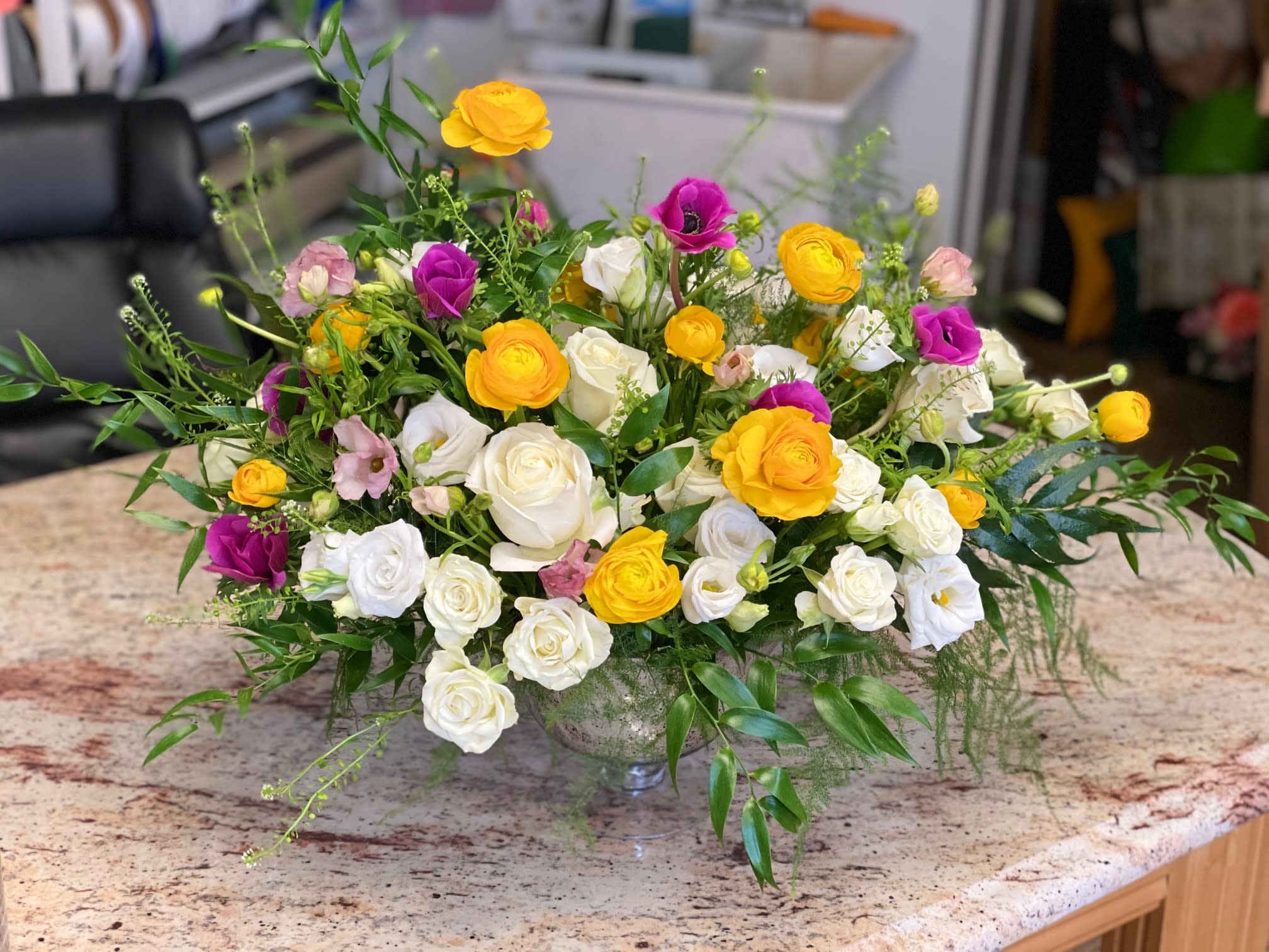 Mixed bouquet of white, yellow, and purple roses in a glass vase