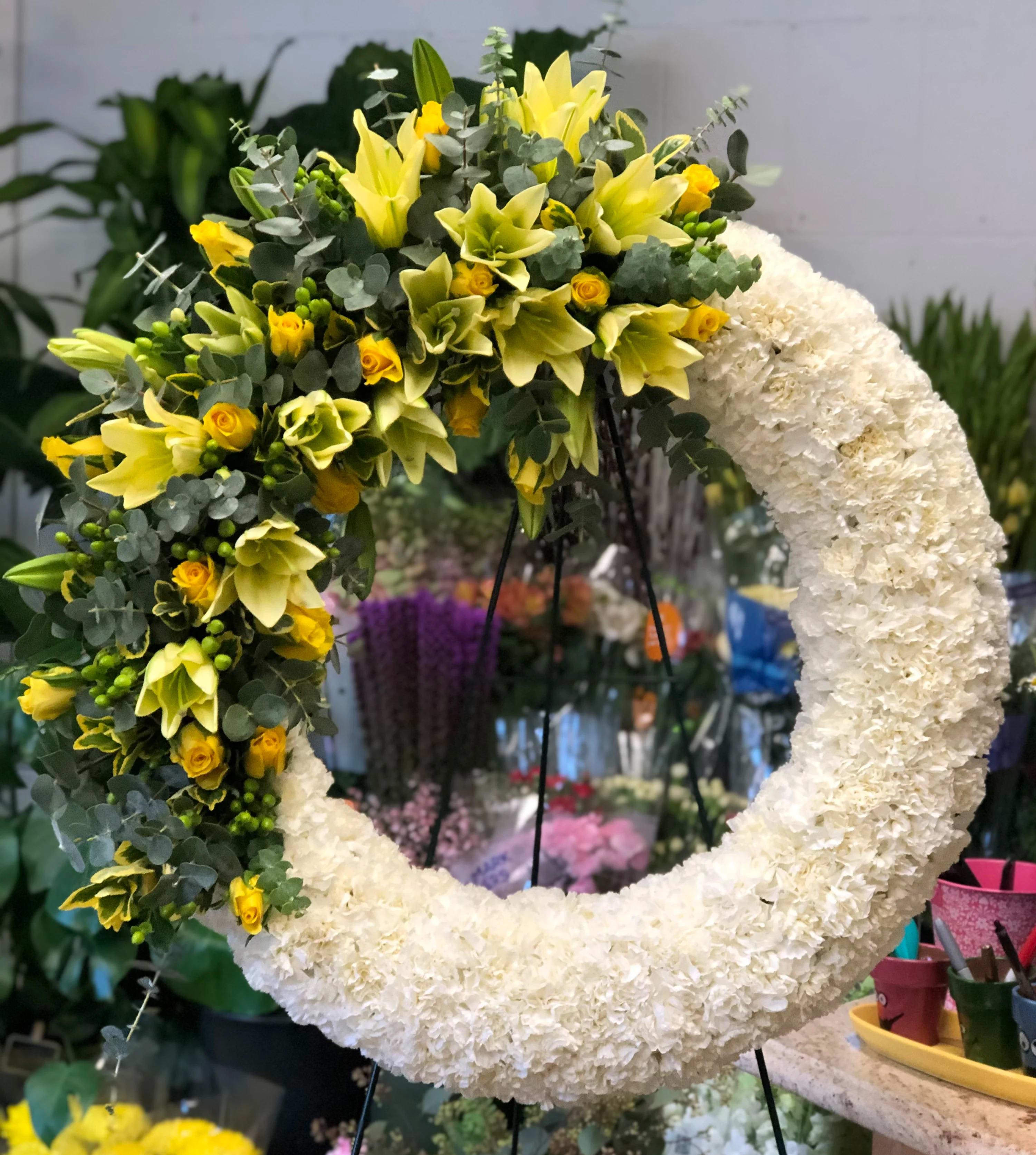 Large floral wreath with white blooms and yellow flowers on one side