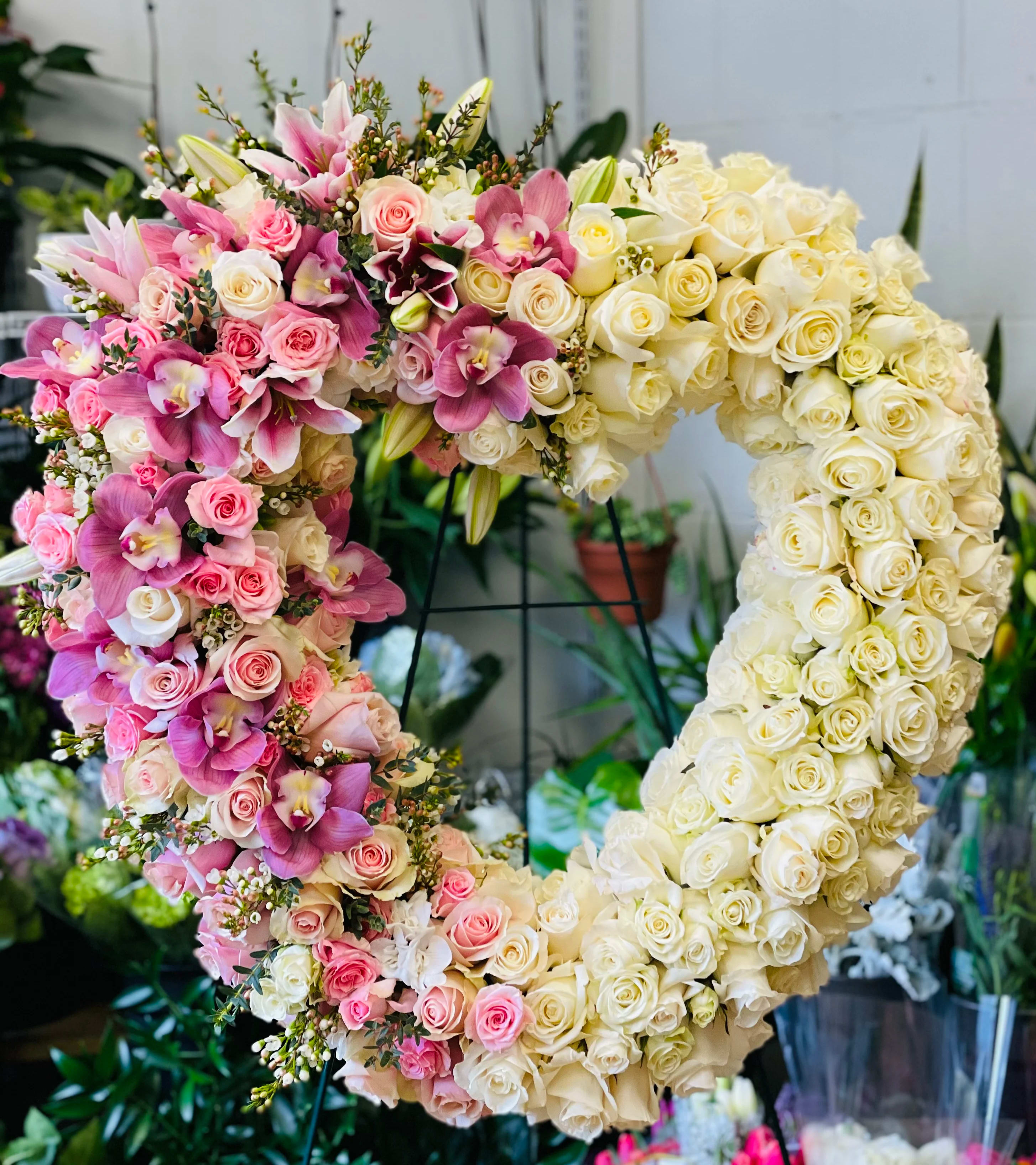 Heart-shaped floral arrangement of pink and cream roses with orchids