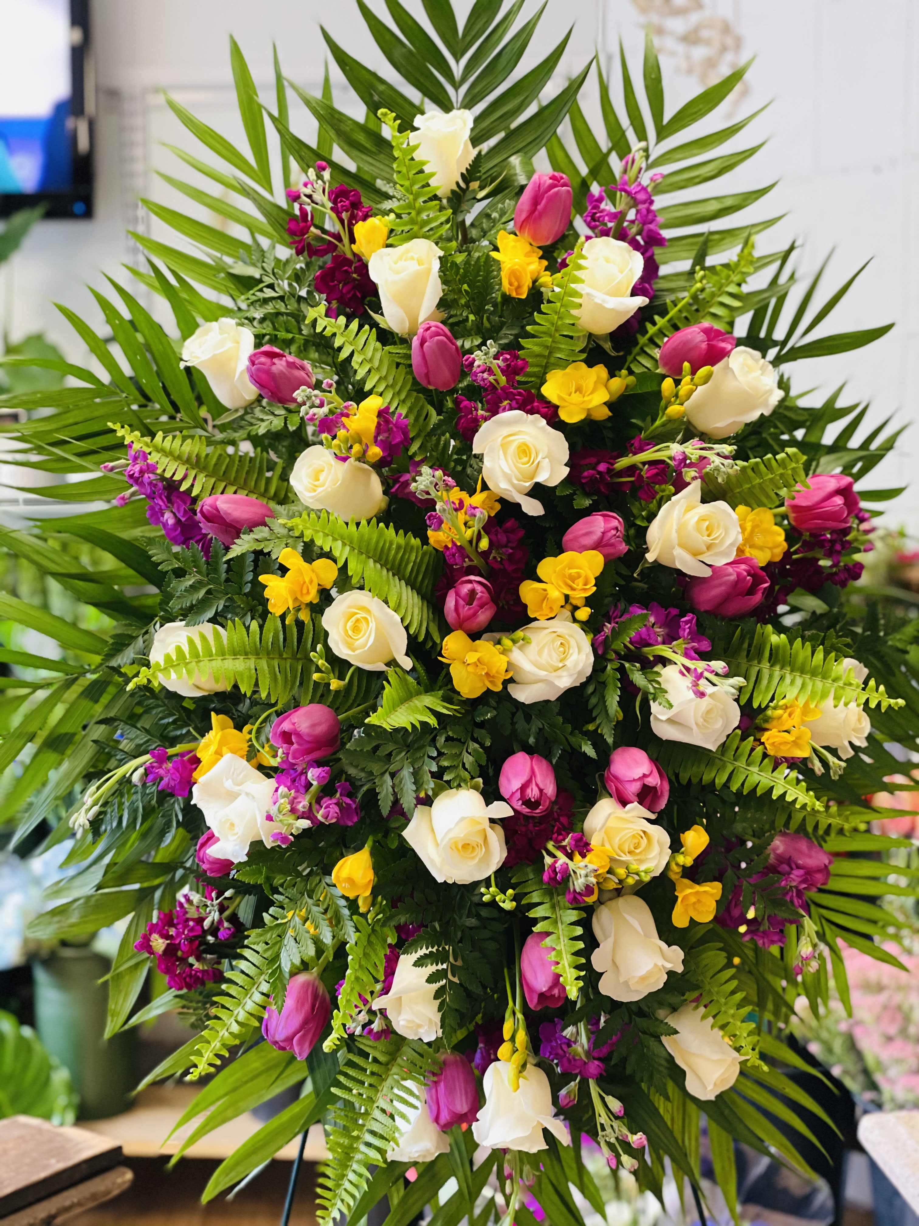 Large floral spray with white roses, pink tulips, and yellow accents