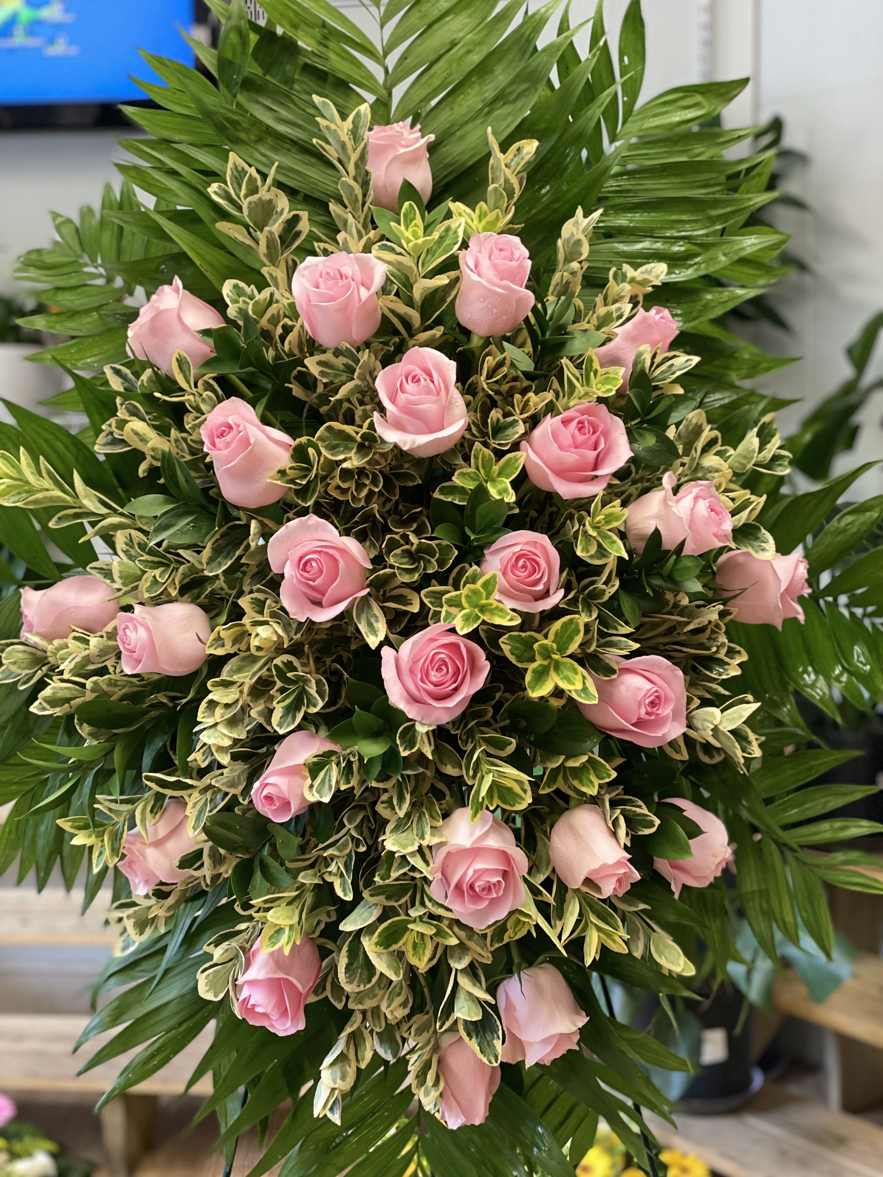 Pink roses arranged in a dense standing spray with variegated foliage
