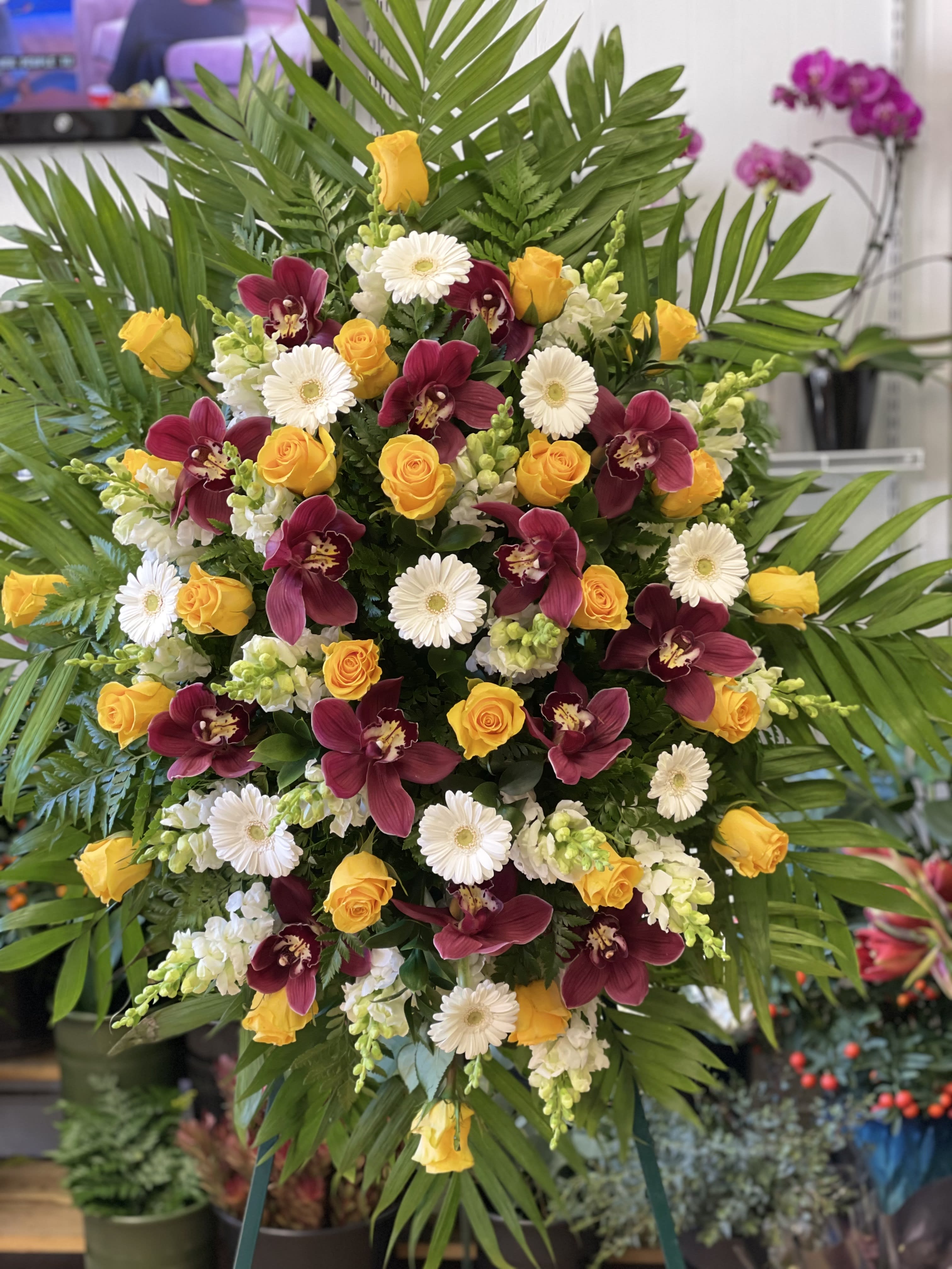 Large standing spray with yellow roses, burgundy orchids, and white daisies