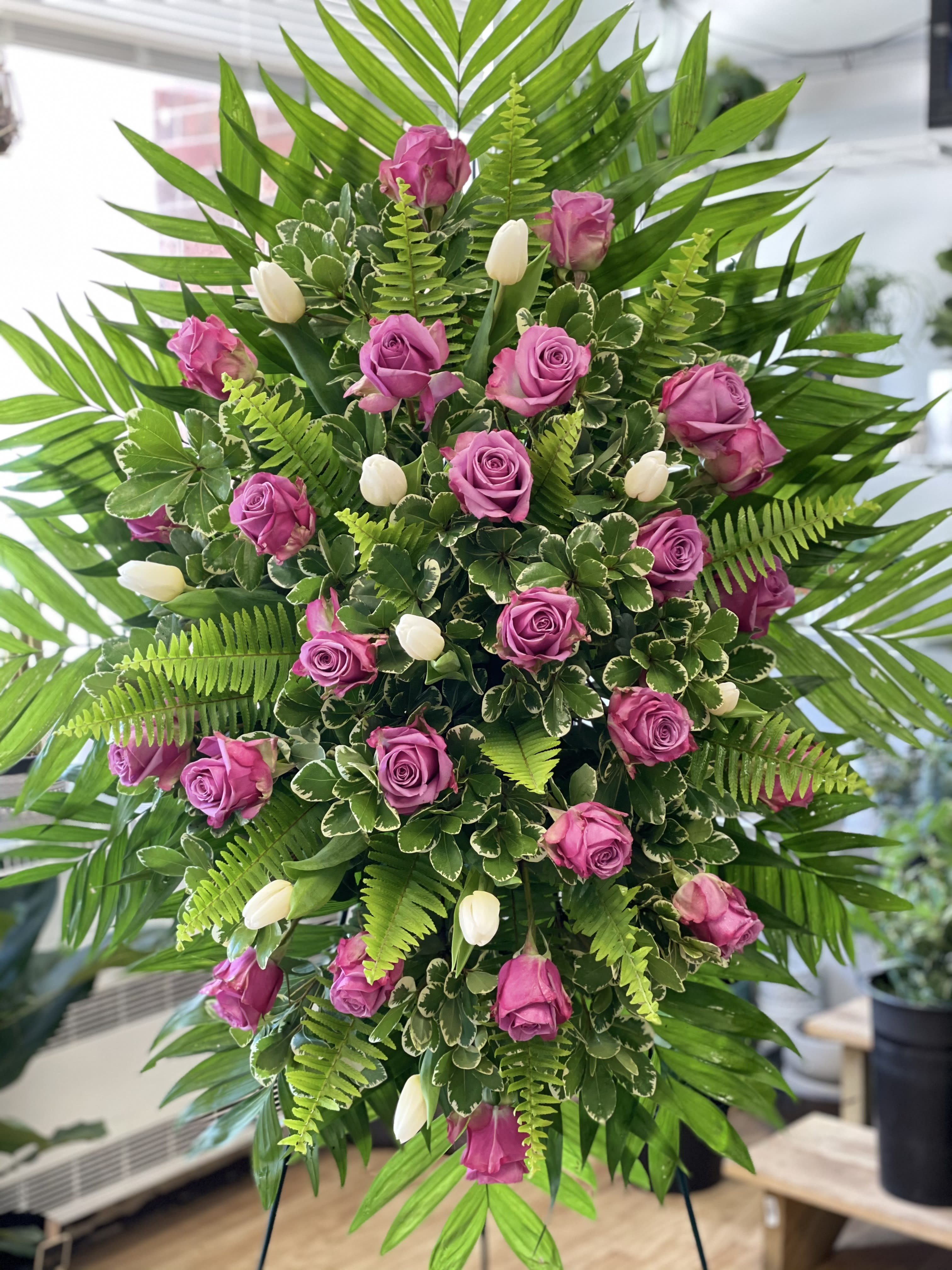 Standing floral spray with pink roses and white tulips surrounded by palm fronds