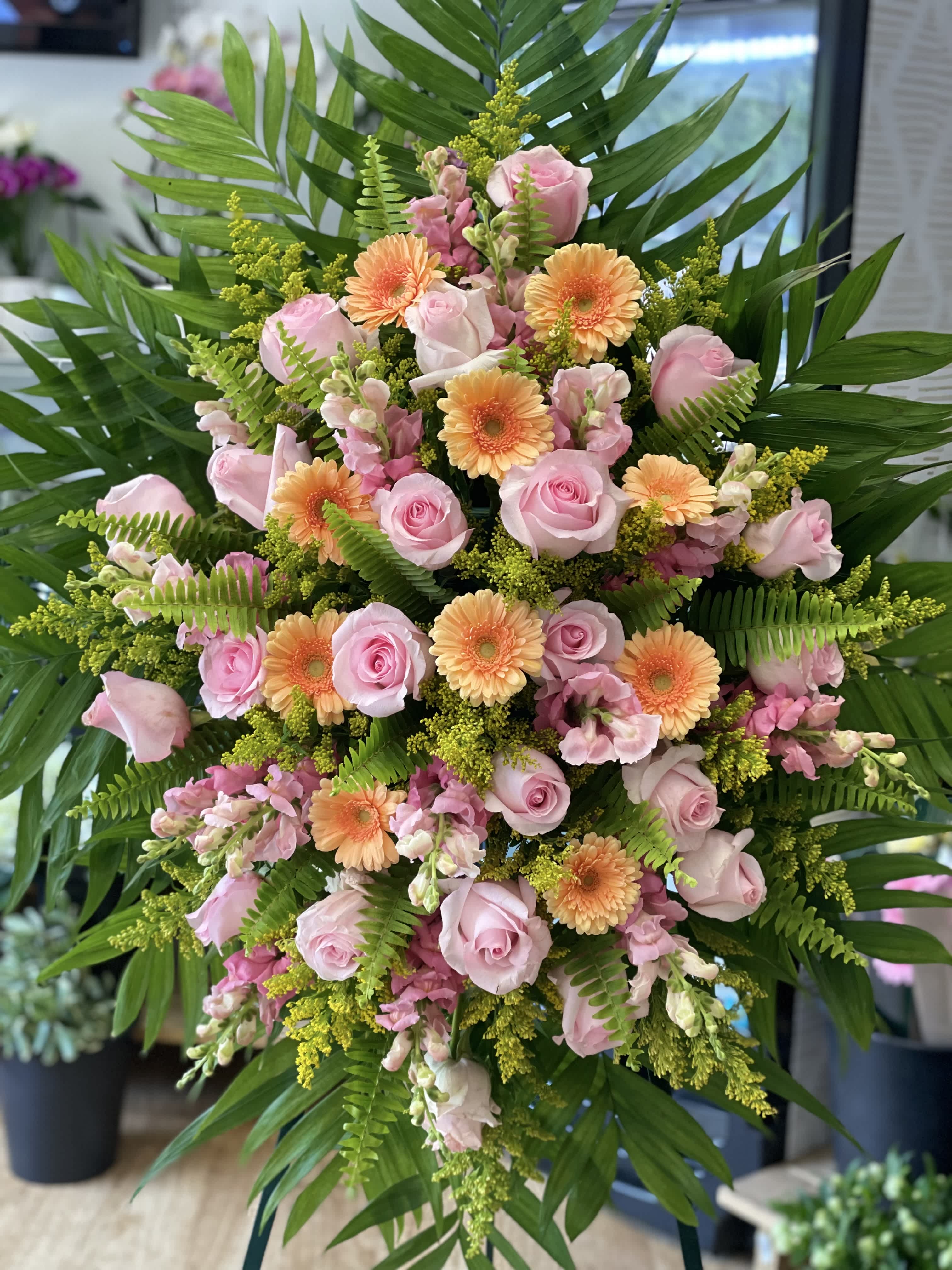 Pink roses and peach gerbera daisies in a large standing arrangement
