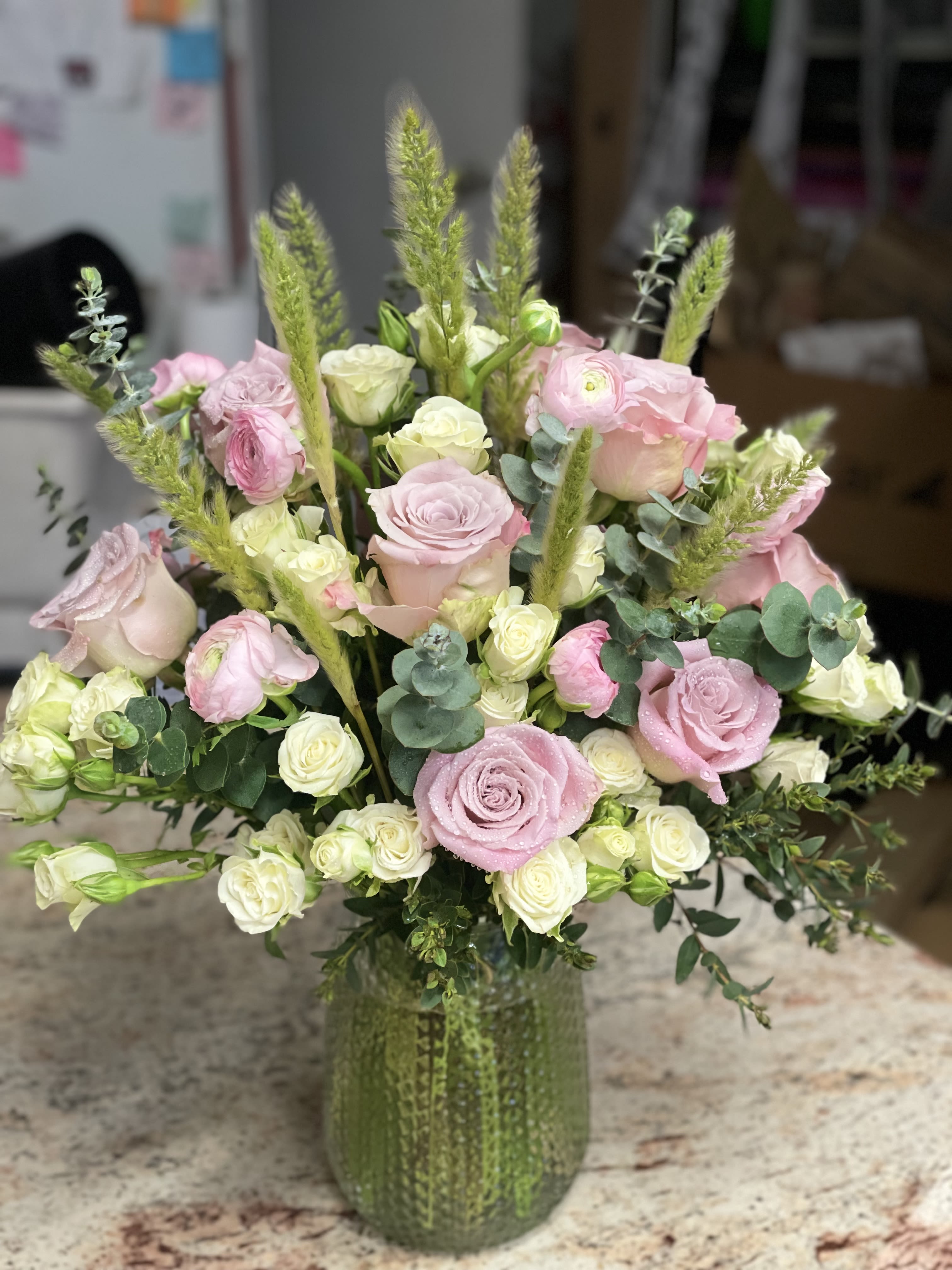 Pink and white roses arranged in a green glass vase