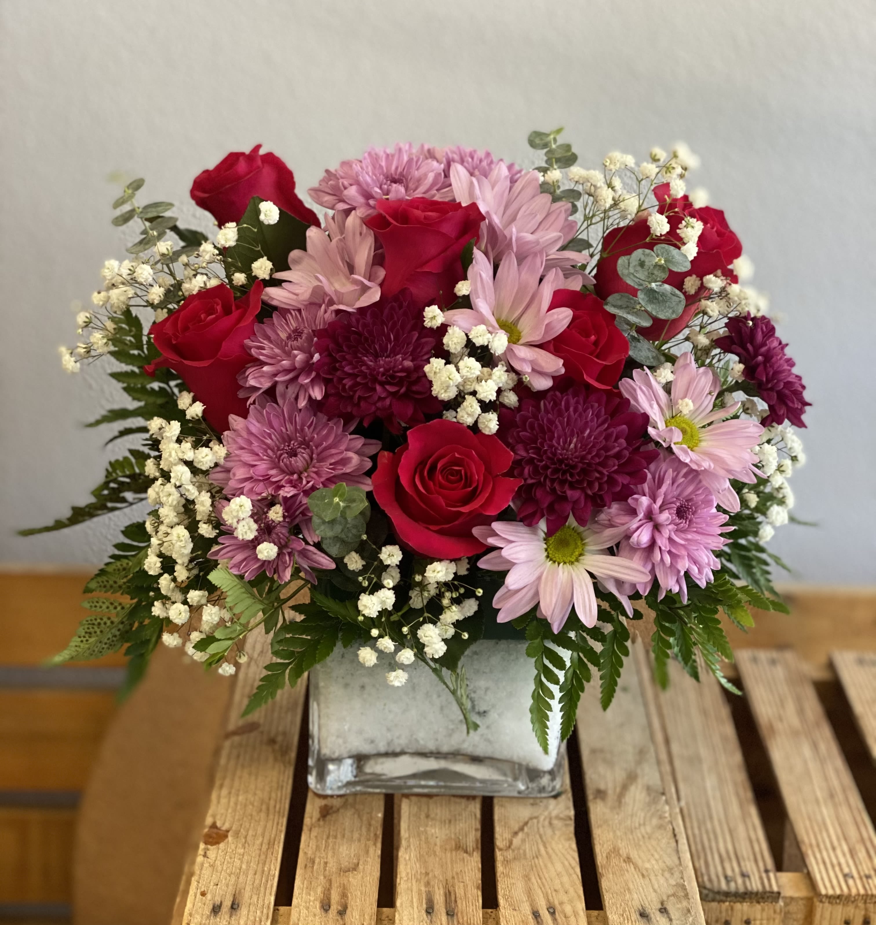 Pink and red flower arrangement in a square glass vase