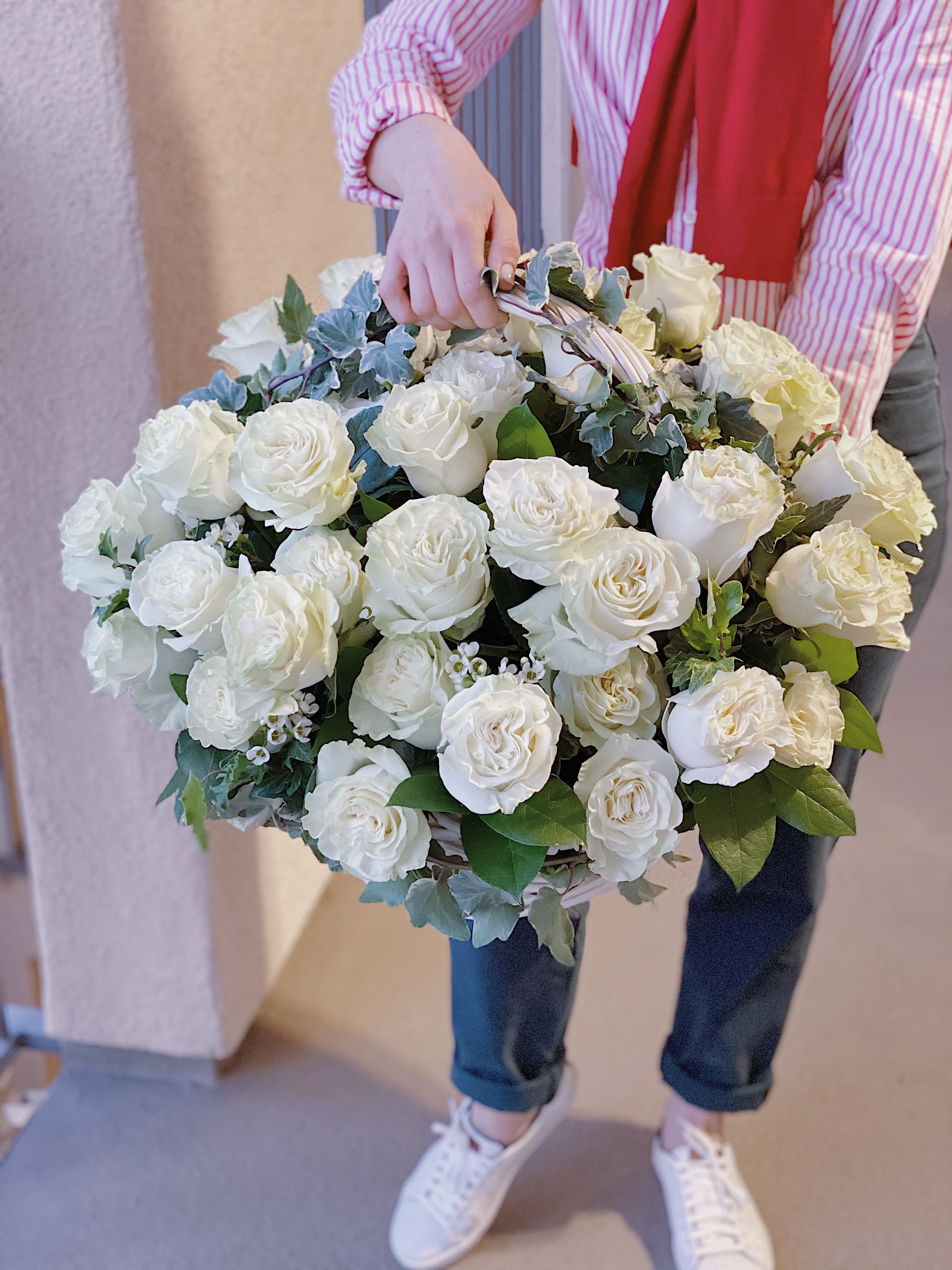Large bouquet of white roses with greenery being held by a person