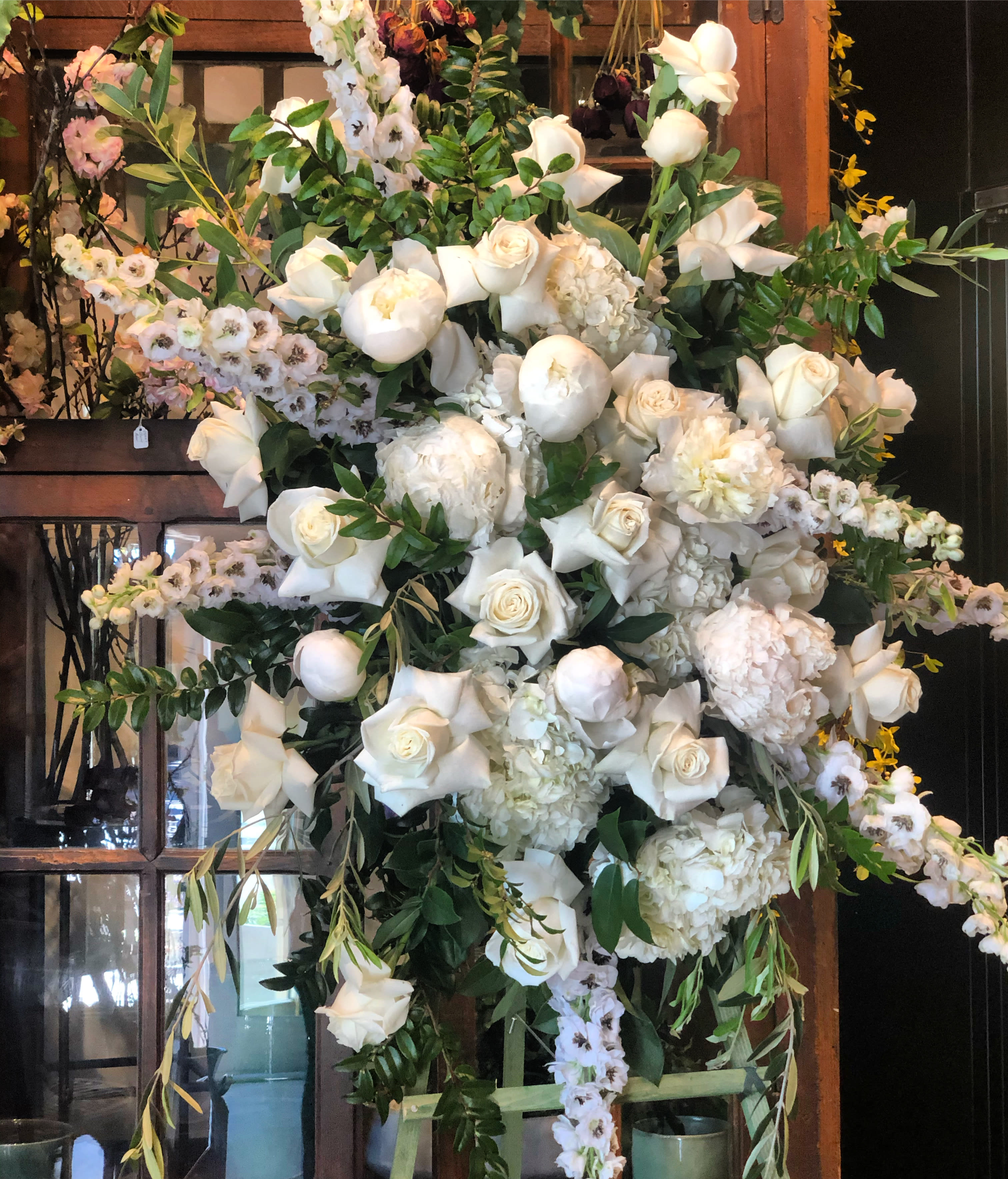 Large white floral arrangement with roses, peonies, and orchids