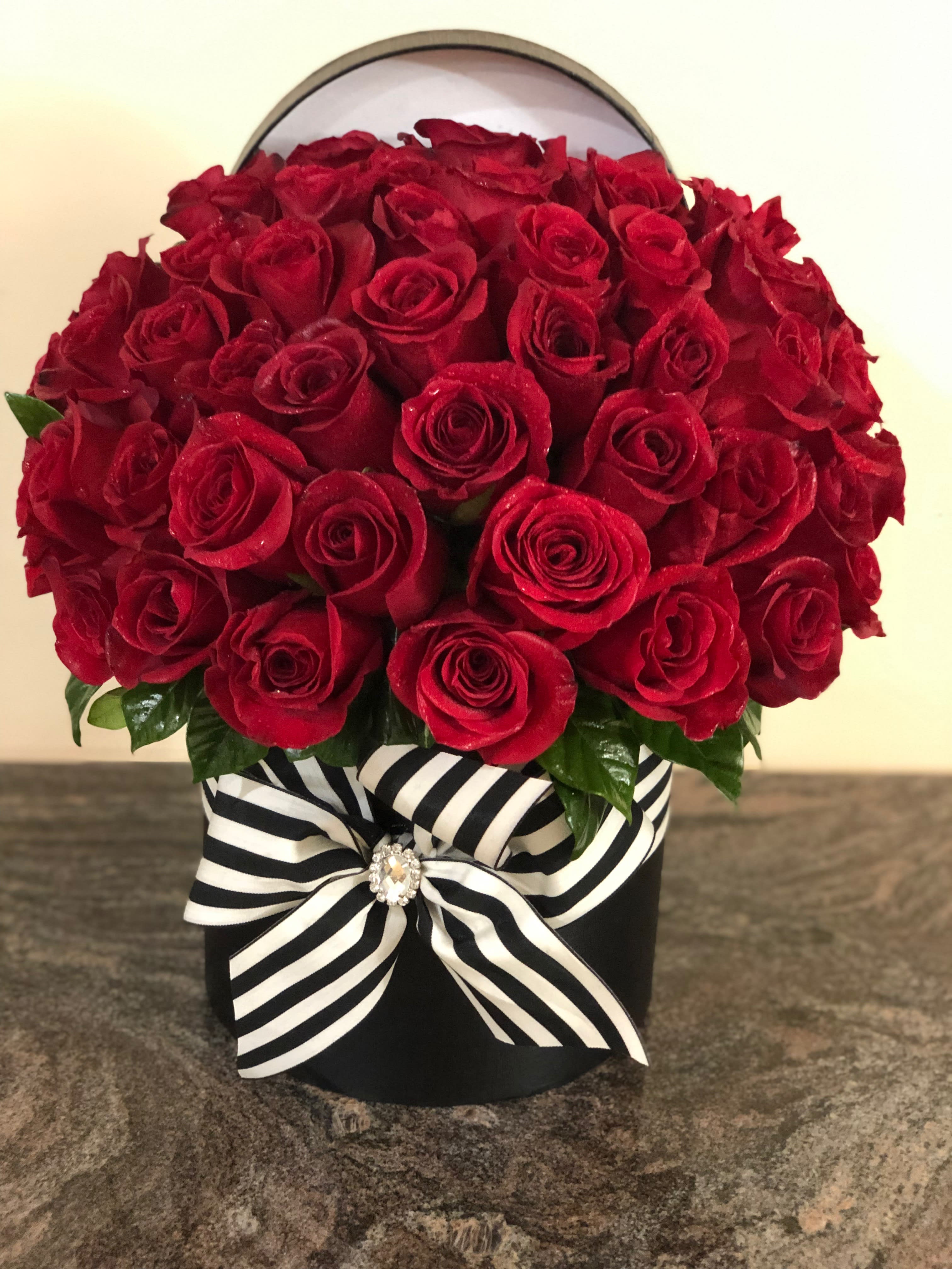 Red rose arrangement in a black box with a striped ribbon