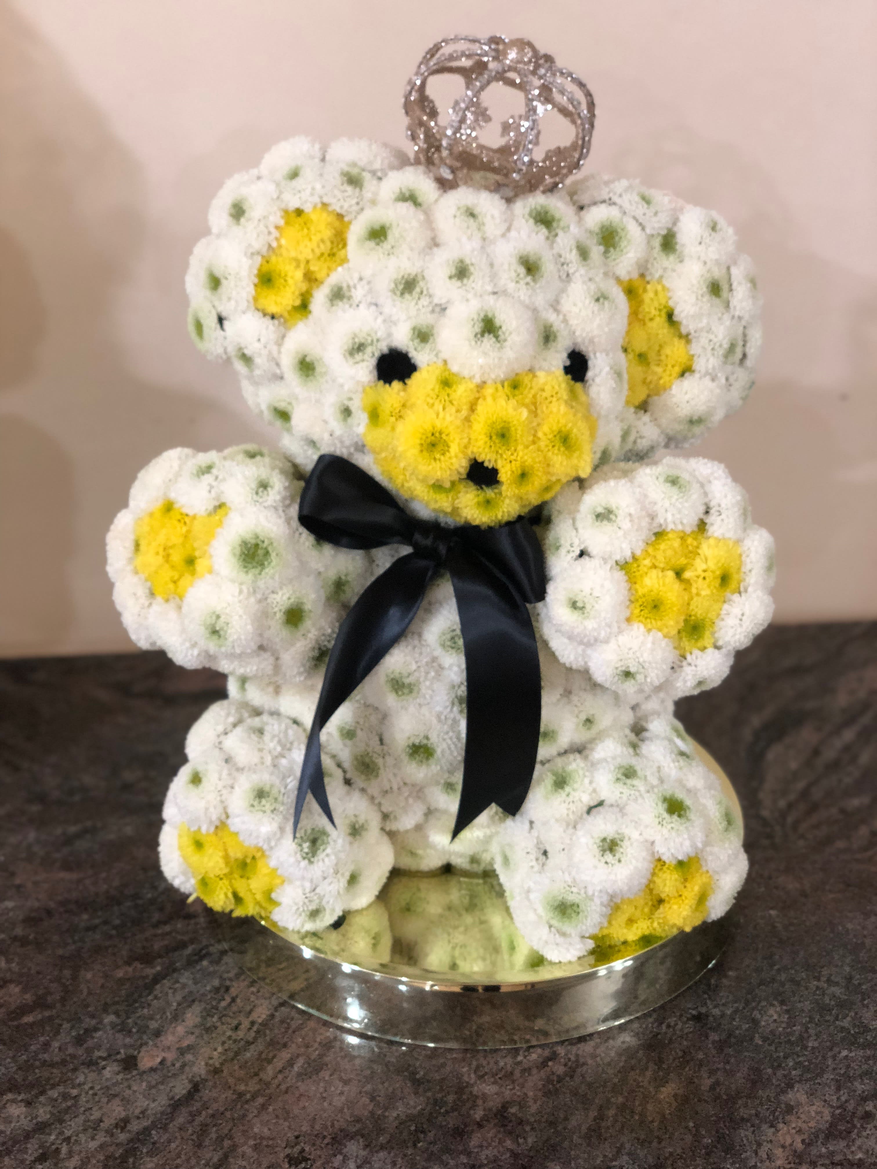 Teddy bear made of white and yellow flowers with a black ribbon