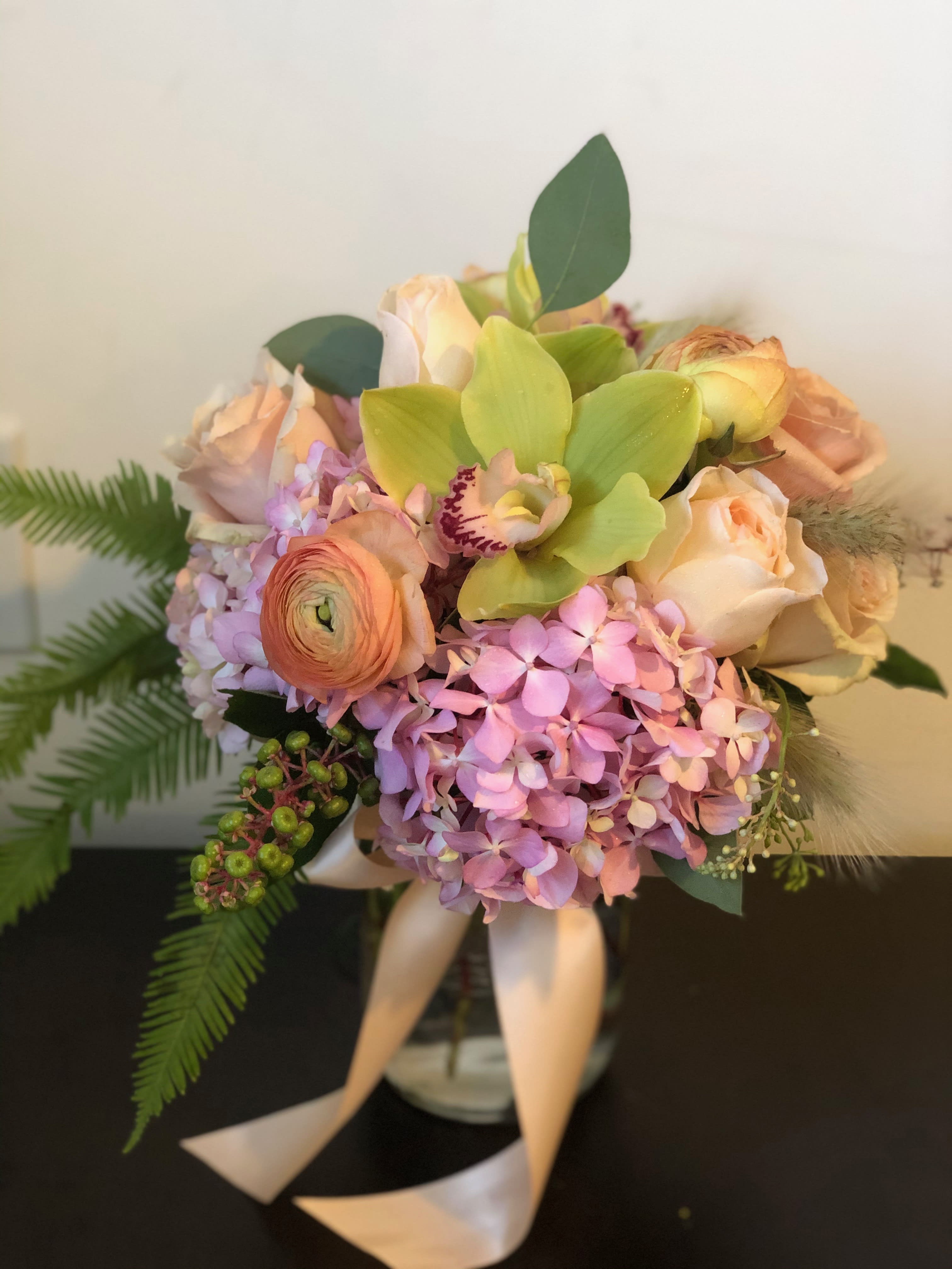 Bouquet of pastel roses, hydrangea, and green orchids with ribbon