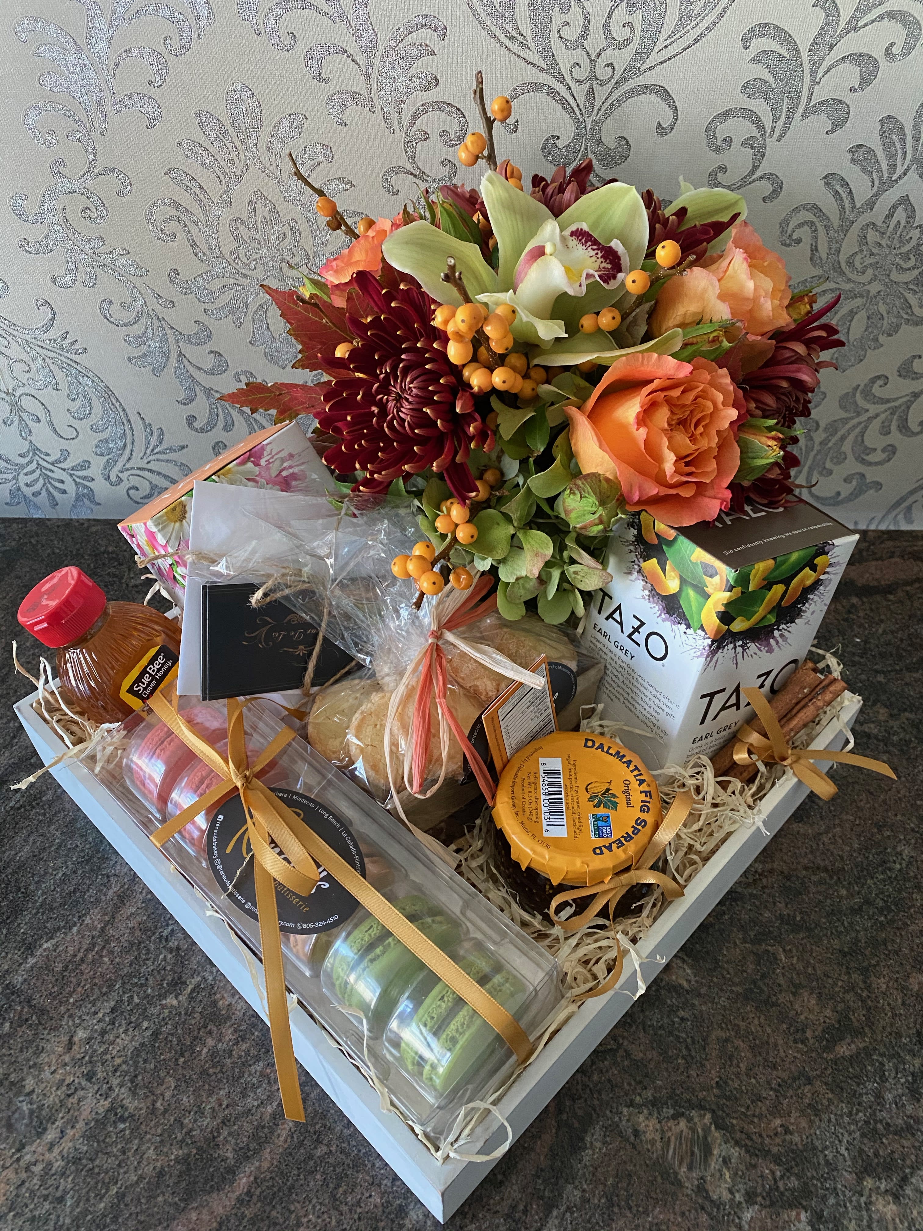 Gift basket with flowers, tea, honey, and packaged treats