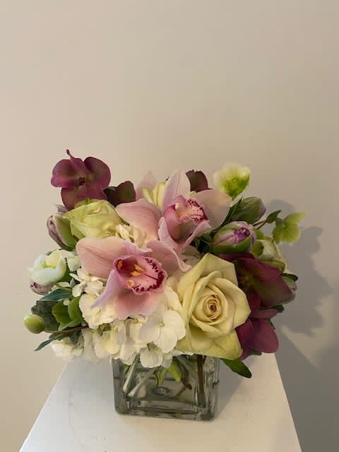 Bouquet of pink orchids and cream roses in a square glass vase