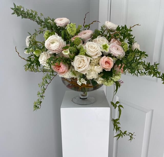 Pastel rose arrangement in a glass compote vase