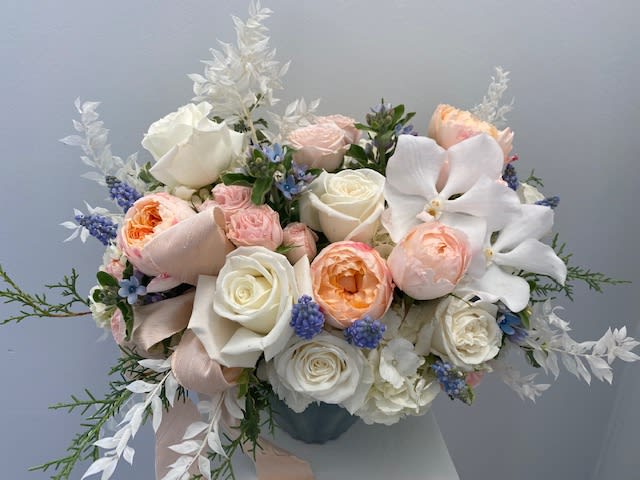 Bouquet of white and blush roses with white orchids in a vase