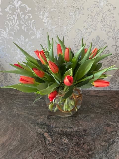 Orange tulips arranged in a clear glass vase