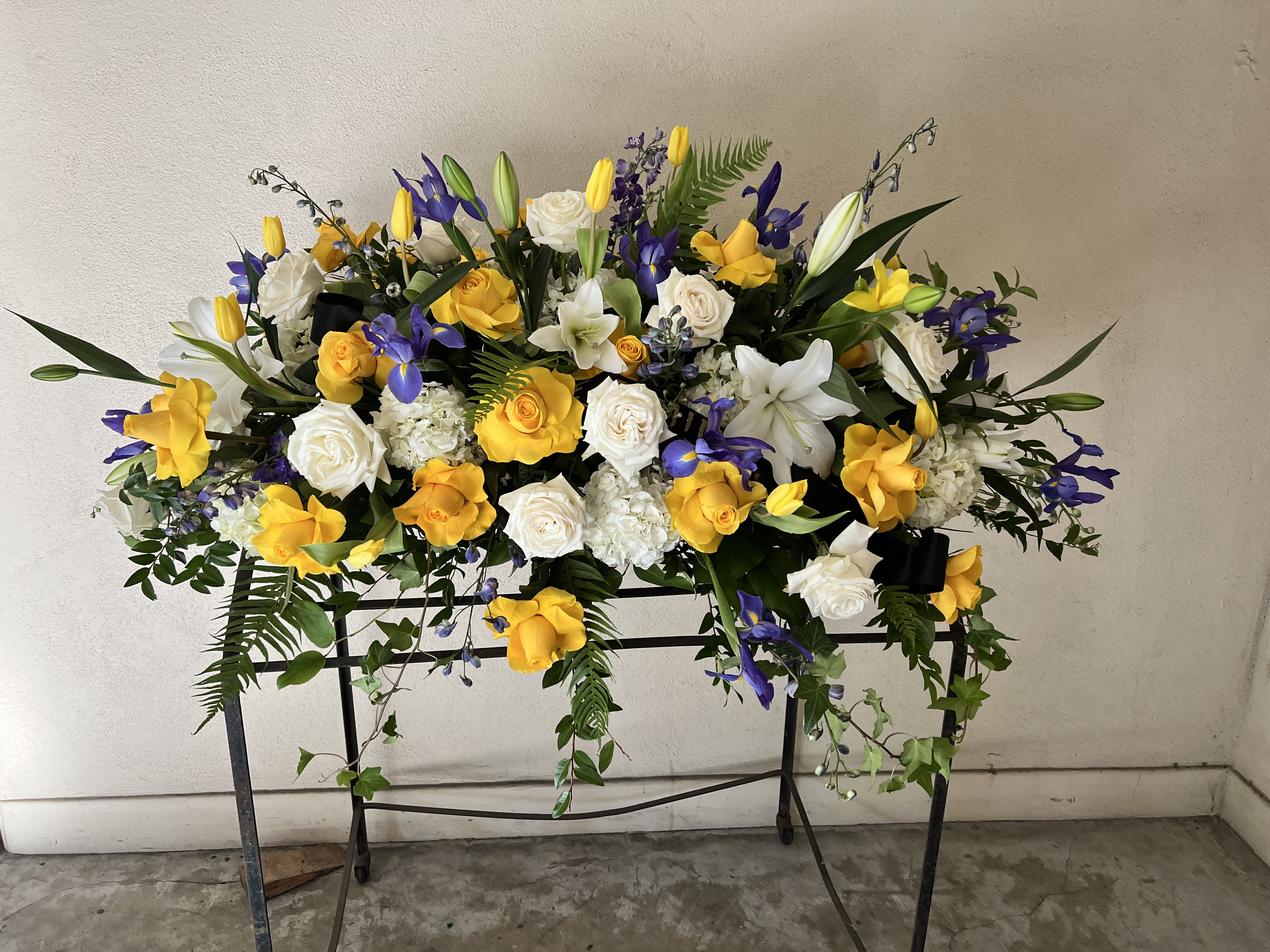Large floral spray with yellow and white roses and purple blooms on a stand