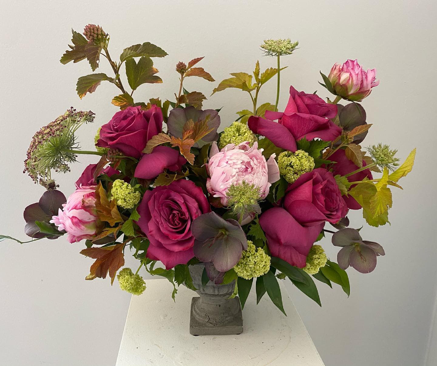 Bouquet of magenta roses and pink peonies in a gray vase