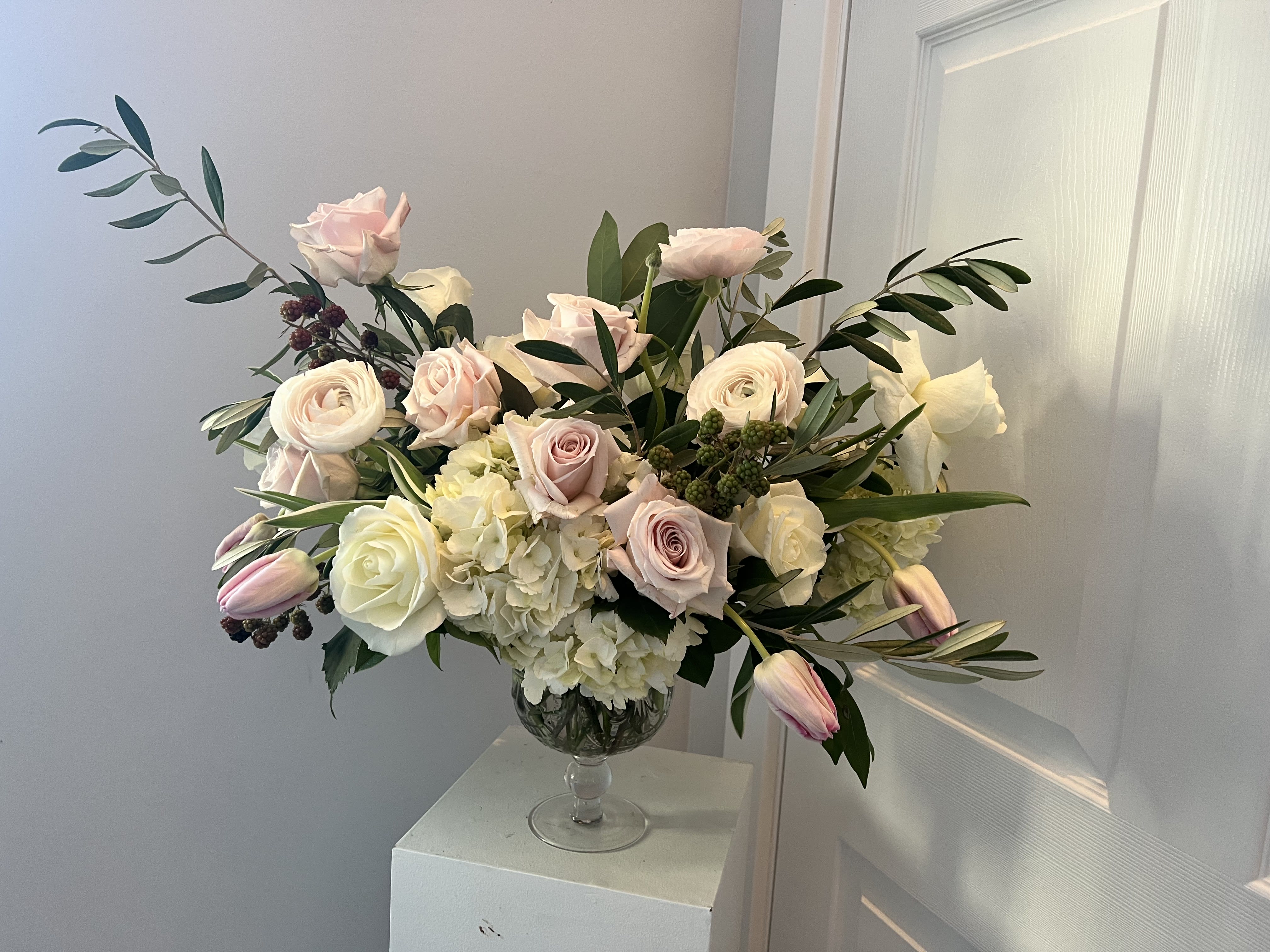 Blush and white roses with tulips in a clear glass vase