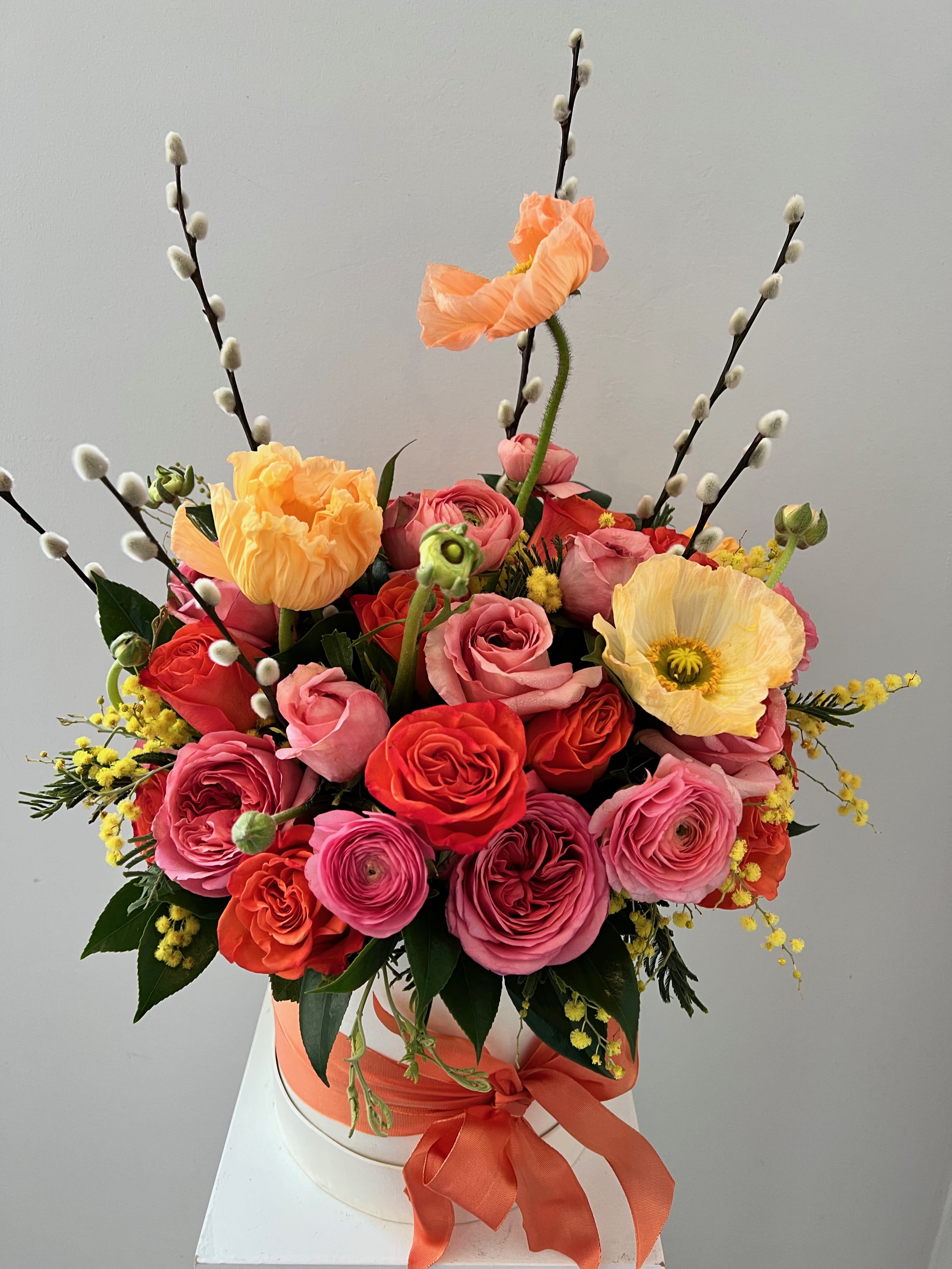 Bouquet of pink and orange roses with poppies in a white hat box