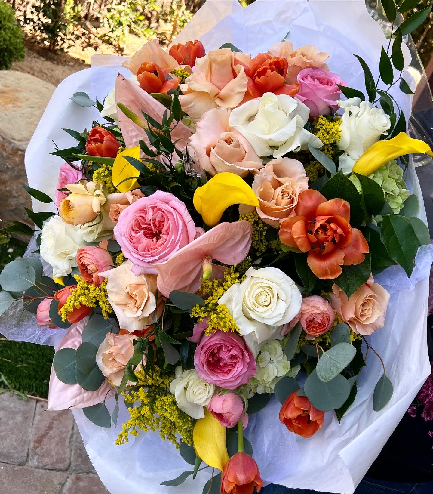 Mixed bouquet of roses, tulips, calla lilies, and anthurium in white wrap
