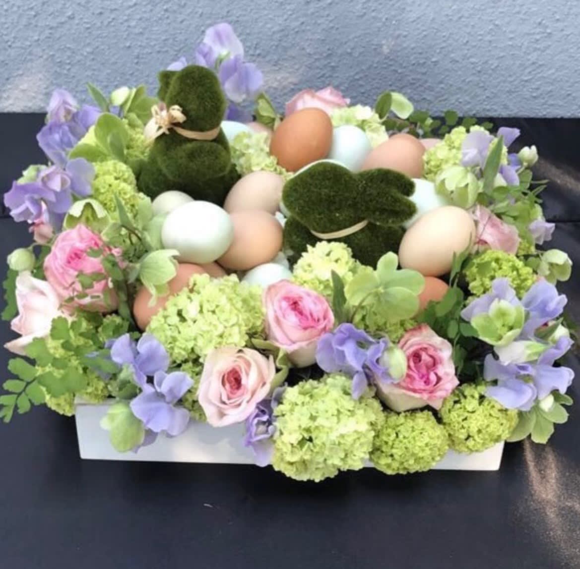Pastel floral arrangement with eggs and moss bunny figures in a white box