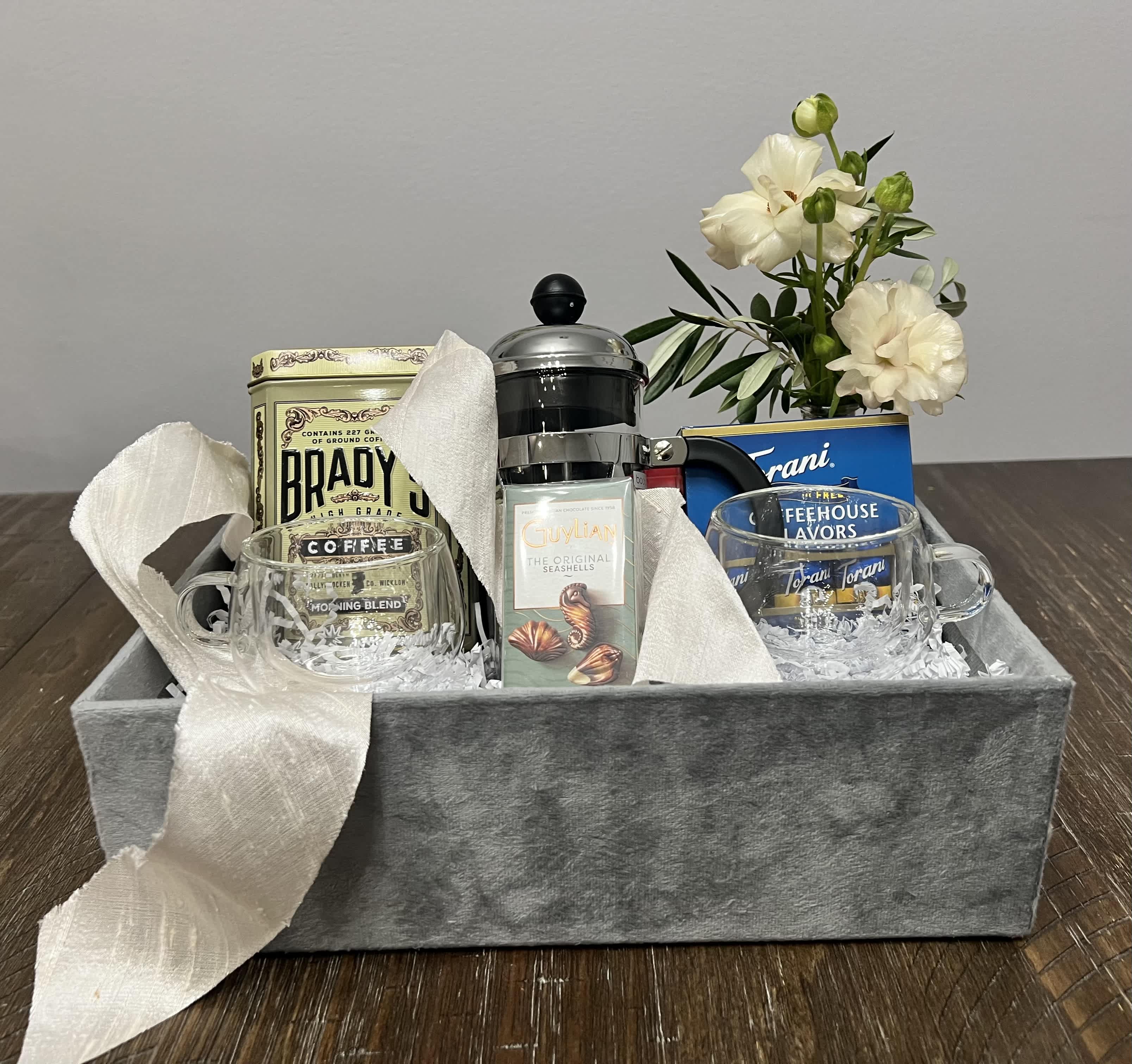 Gift basket with coffee, mugs, tea, and white flowers