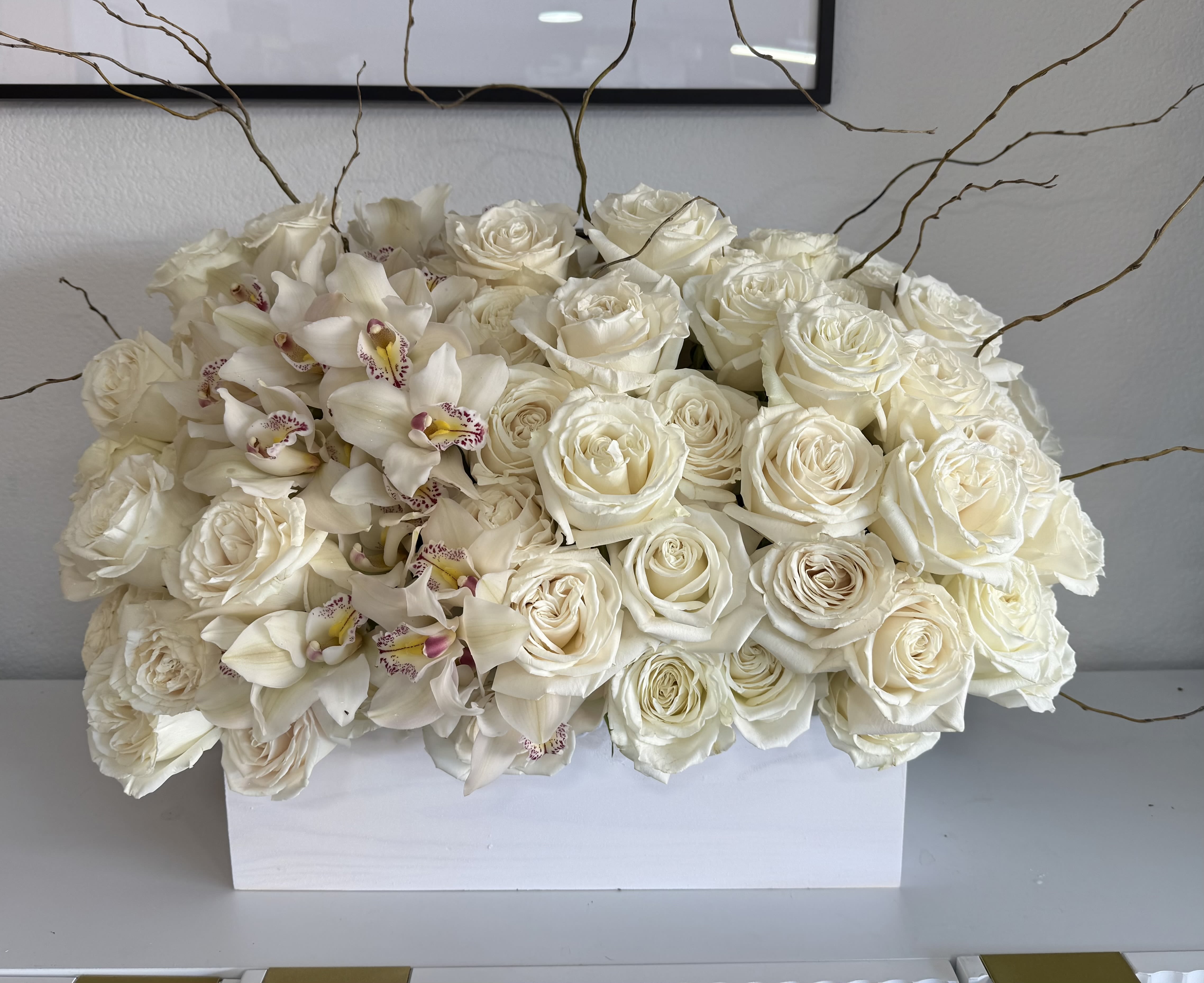 White roses and orchids arranged in a rectangular white box