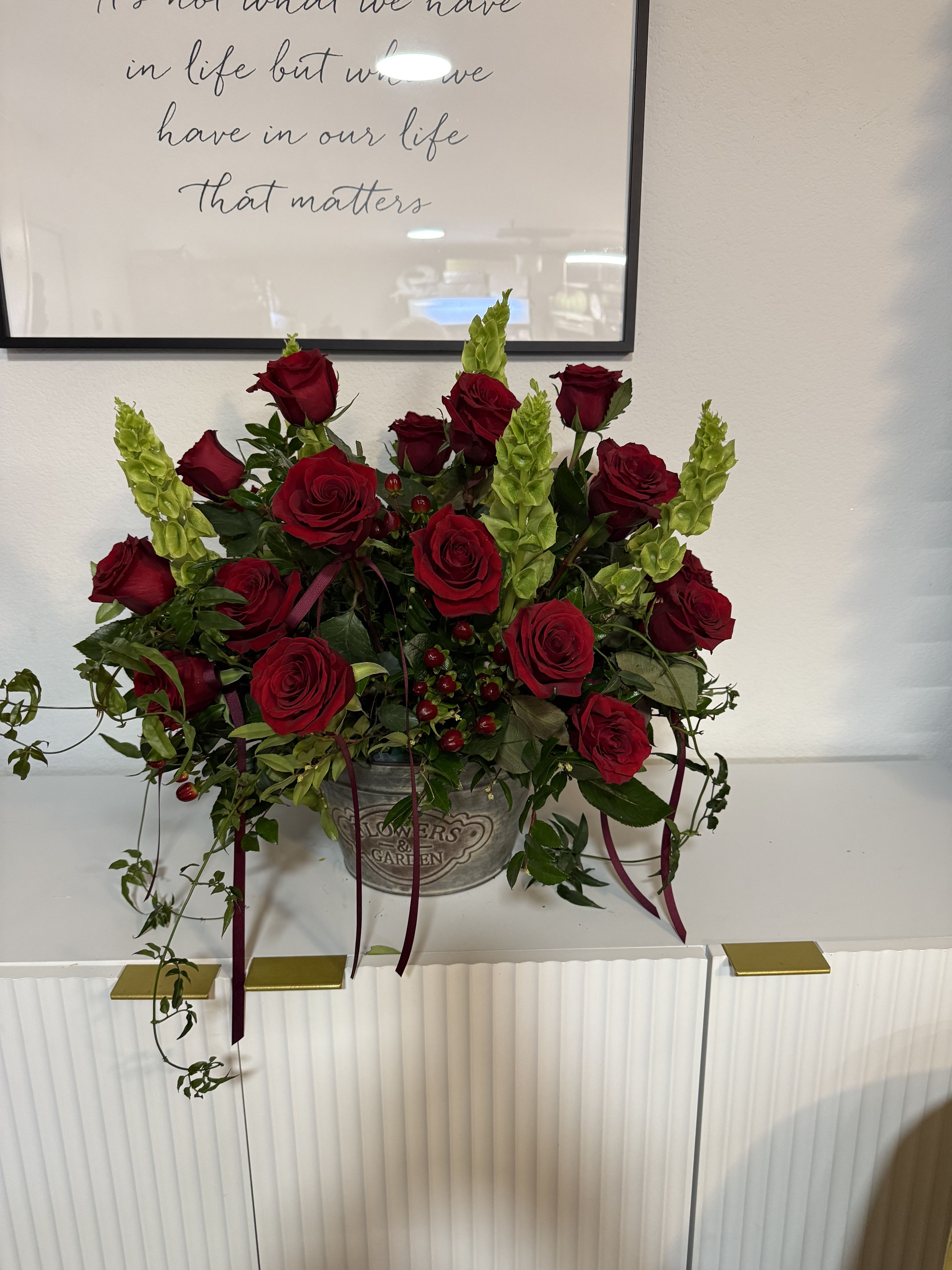 Red roses and green spikes arranged in a metal container