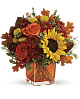 Autumn bouquet with sunflowers and roses in an orange vase