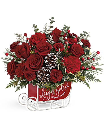Red roses arranged in a sleigh-shaped container with pinecones and berries