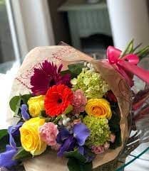 Bouquet of mixed colorful flowers wrapped in paper with a pink ribbon