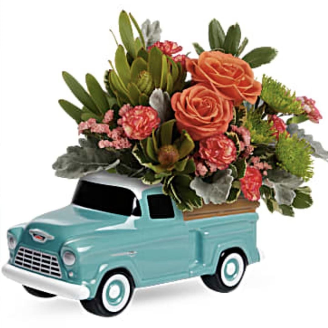 Mini truck figurine topped with orange flowers and greenery