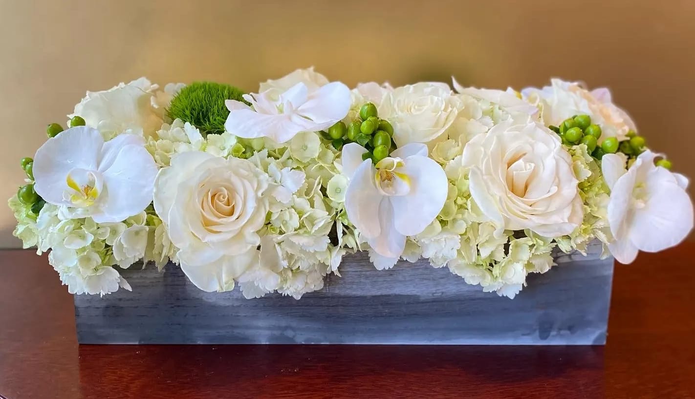 White roses and orchids in a rectangular wooden box