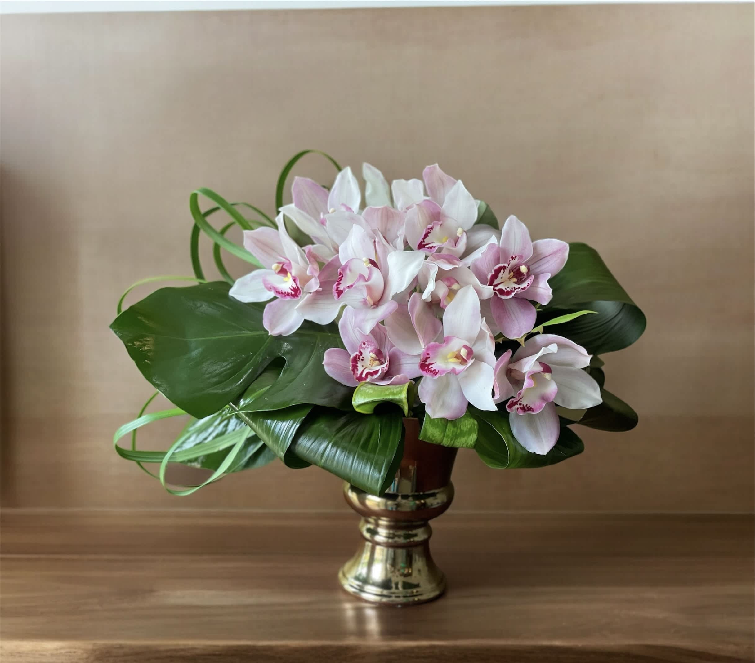 Pink and white orchids arranged in a gold vase
