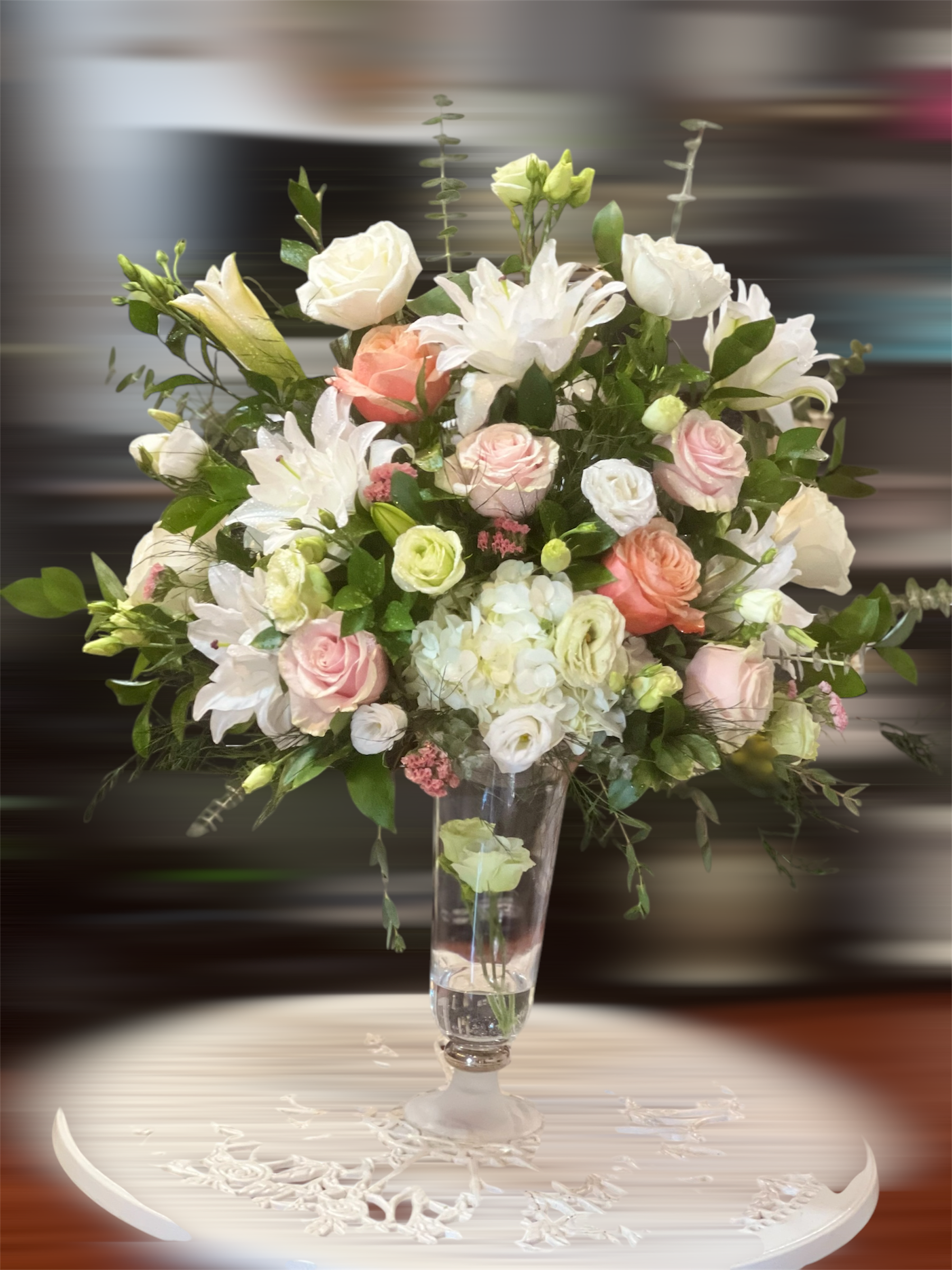 Tall bouquet of white and blush flowers in a clear glass vase