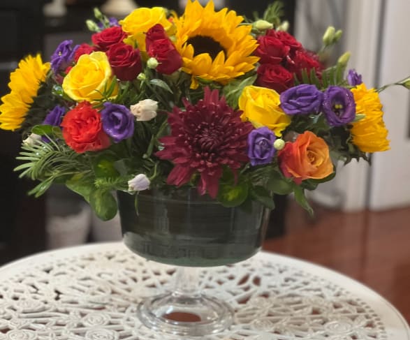 Mixed bouquet of roses, sunflowers, and chrysanthemums in a glass vase