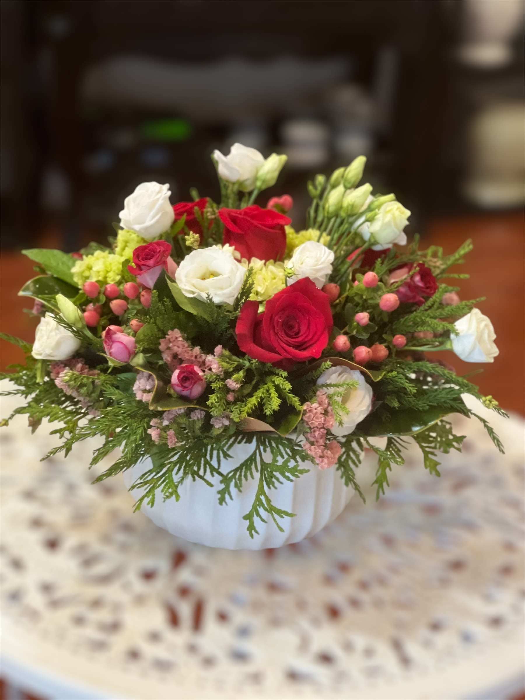 Red and white rose arrangement in a white vase